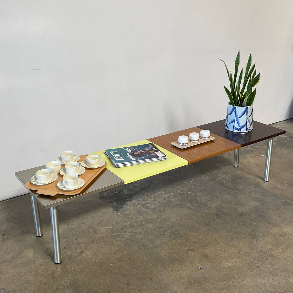 The Mazzei Multi-Panel Table by Mazzei is a contemporary design featuring a bench with a vibrant yellow, green, and blue top that adds functionality to any space.