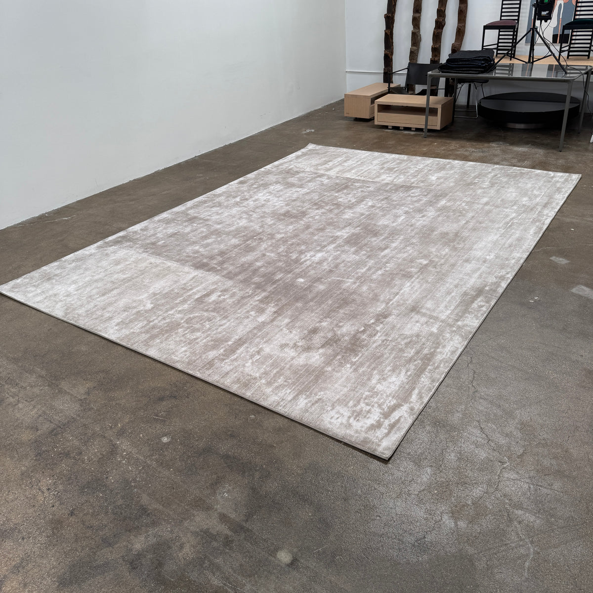 A close-up view of the Limited Edition 10 x 13.5′ Silk Rug, a rectangular, light gray area rug featuring a subtle textured pattern, crafted by the renowned Belgian brand Limited Edition. The luxurious silk rug is photographed against a plain white background.