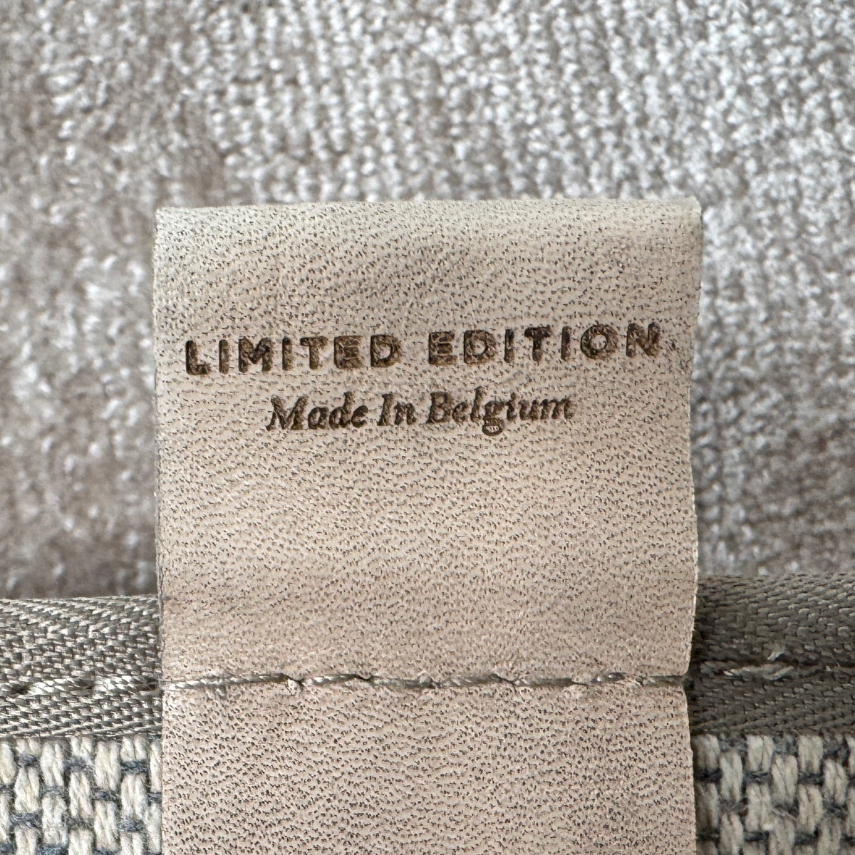 A close-up view of the Limited Edition 10 x 13.5′ Silk Rug, a rectangular, light gray area rug featuring a subtle textured pattern, crafted by the renowned Belgian brand Limited Edition. The luxurious silk rug is photographed against a plain white background.