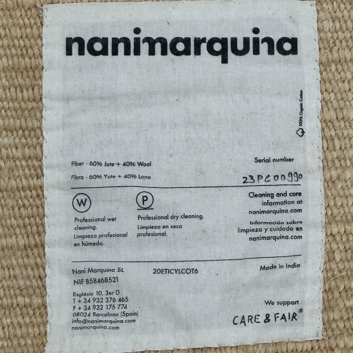 A rectangular Nanimarquina Tres Rug in Ocher, showcasing a patchwork design in warm beige and brown hues, is displayed on a concrete floor. This artisanal piece by Nanimarquina features hand-woven techniques and decorative fringe along two opposite edges, reminiscent of the brand’s signature style.