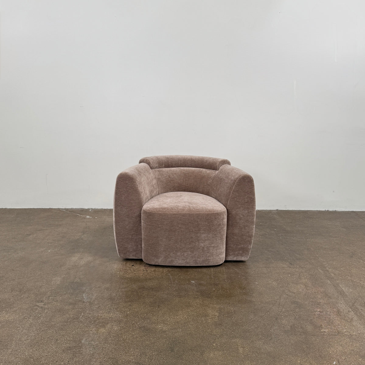 Two Daniel Boddam Wave Lounge Chairs in Maharam Mohair, featuring plush taupe upholstery with rounded backs and arms, are arranged side by side on a polished concrete floor against a plain white wall.