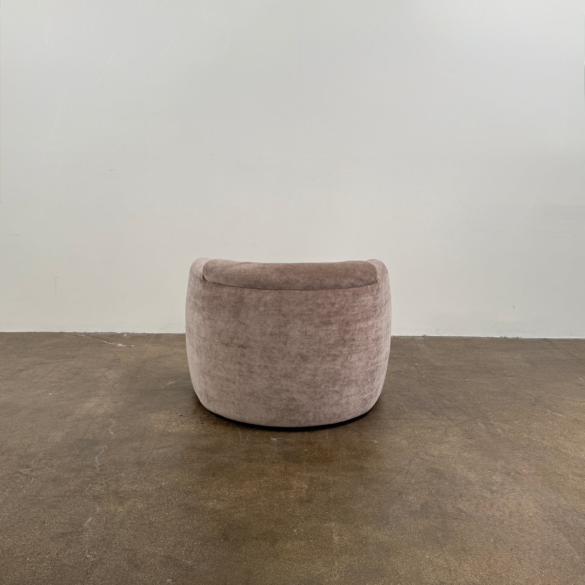 Two Daniel Boddam Wave Lounge Chairs in Maharam Mohair, featuring plush taupe upholstery with rounded backs and arms, are arranged side by side on a polished concrete floor against a plain white wall.