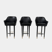 A set of three Stellar Works Lunar Bar Chairs by Steller Works, featuring black leather upholstery, armrests, and gold accents, is arranged in a row against a plain white background.