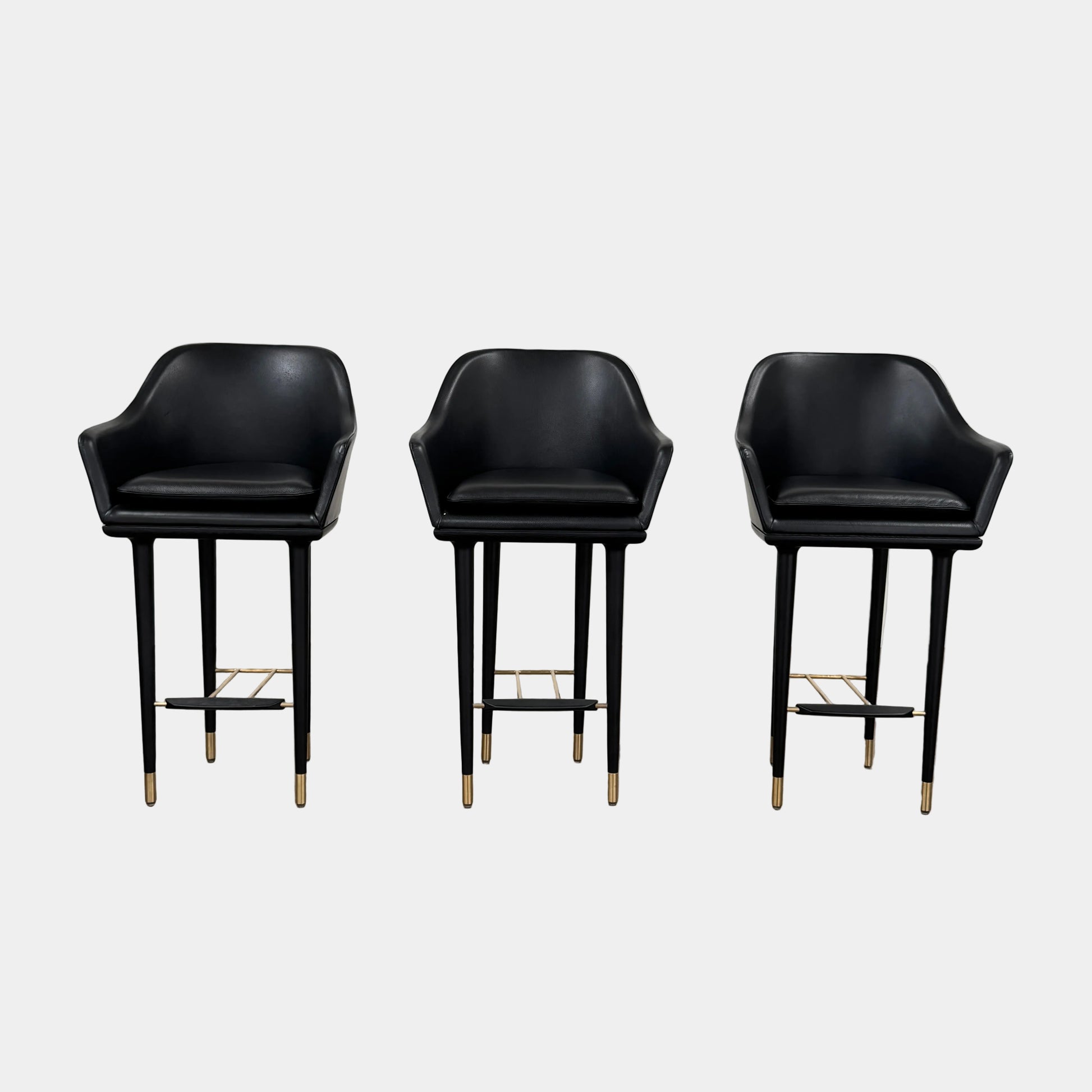 A set of three Stellar Works Lunar Bar Chairs by Steller Works, featuring black leather upholstery, armrests, and gold accents, is arranged in a row against a plain white background.