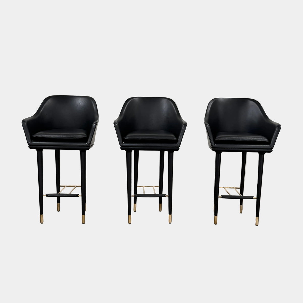 A set of three Stellar Works Lunar Bar Chairs by Steller Works, featuring black leather upholstery, armrests, and gold accents, is arranged in a row against a plain white background.