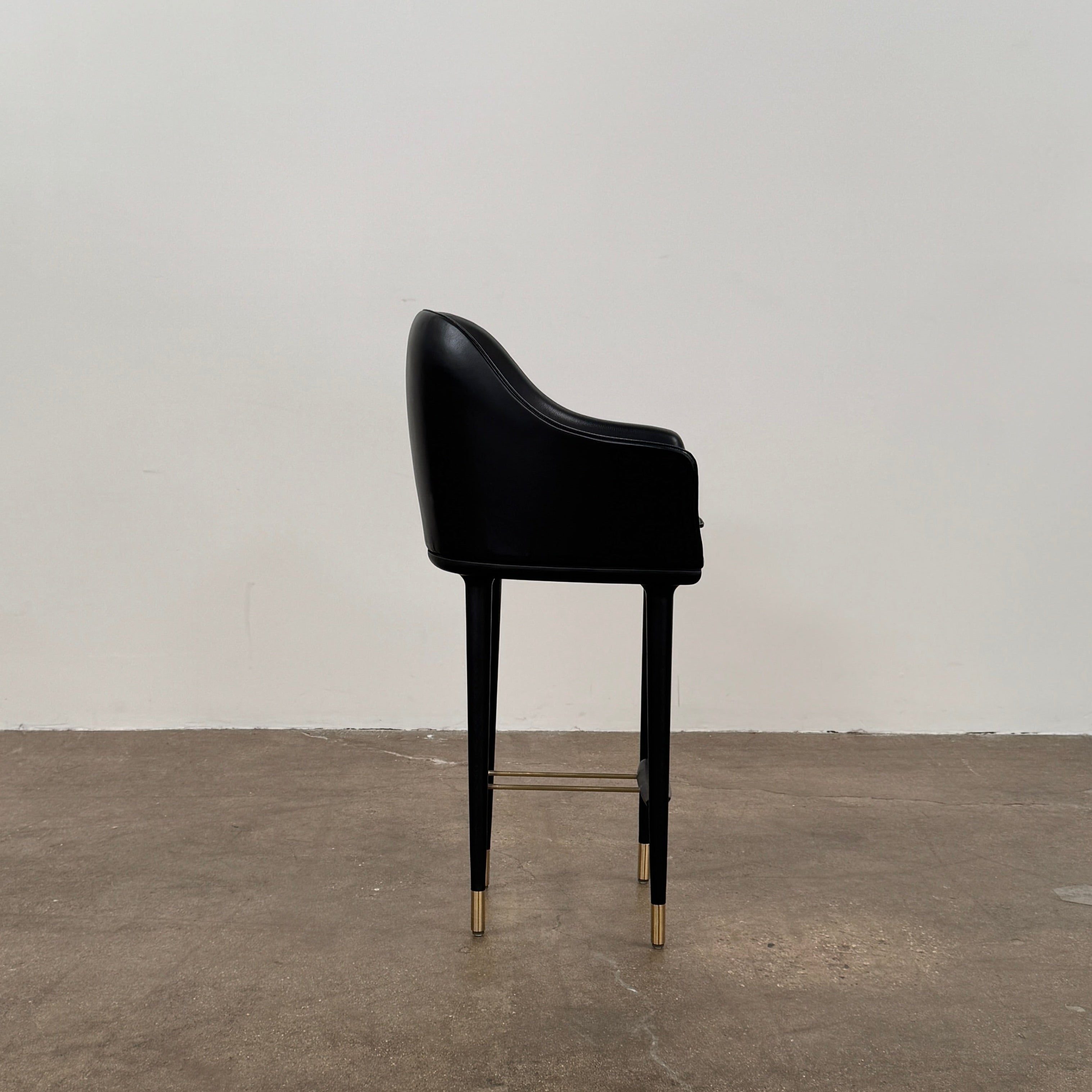 A set of three Stellar Works Lunar Bar Chairs by Steller Works, featuring black leather upholstery, armrests, and gold accents, is arranged in a row against a plain white background.