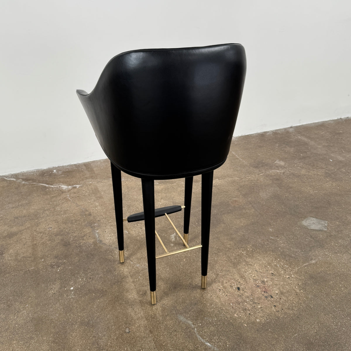 A set of three Stellar Works Lunar Bar Chairs by Steller Works, featuring black leather upholstery, armrests, and gold accents, is arranged in a row against a plain white background.