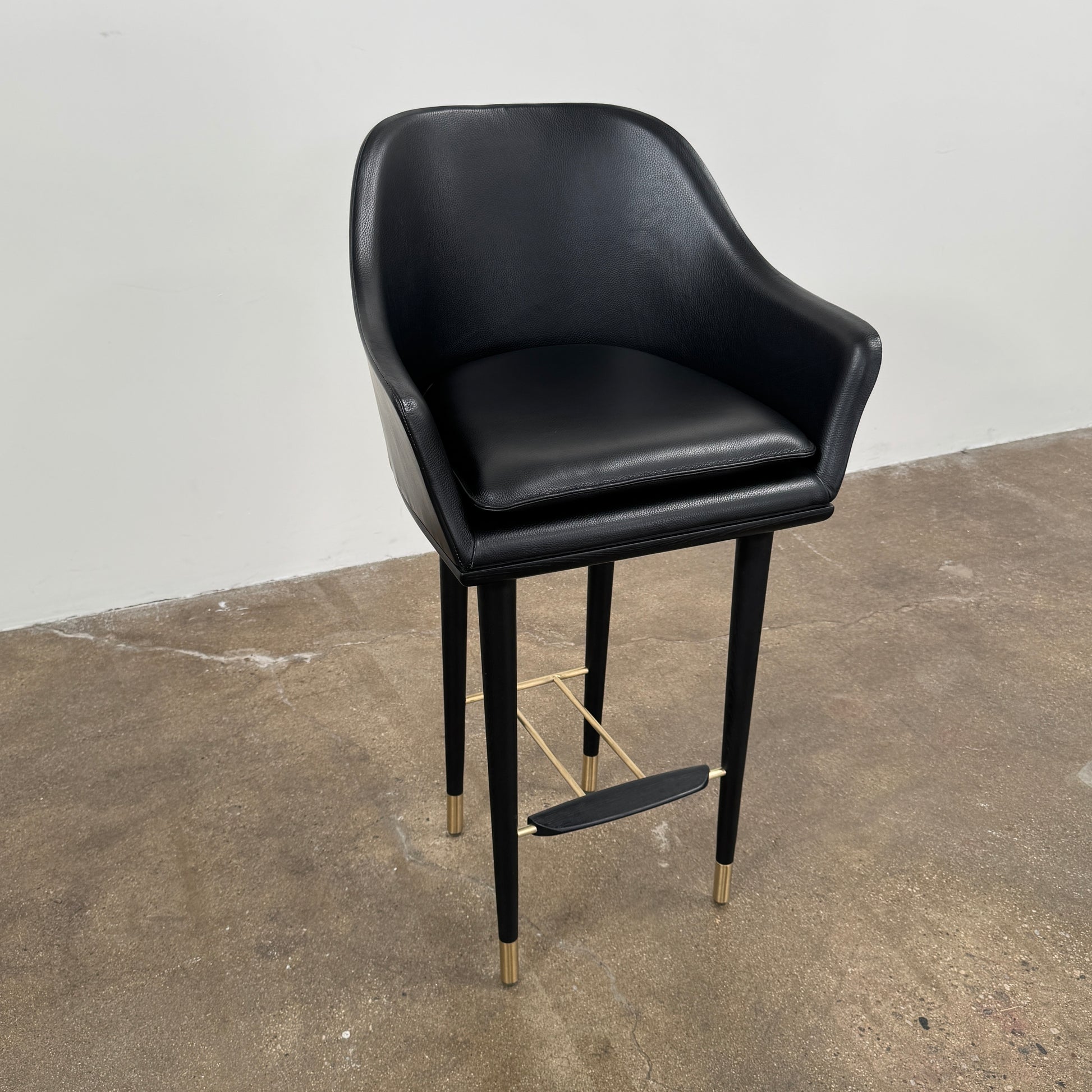 A set of three Stellar Works Lunar Bar Chairs by Steller Works, featuring black leather upholstery, armrests, and gold accents, is arranged in a row against a plain white background.