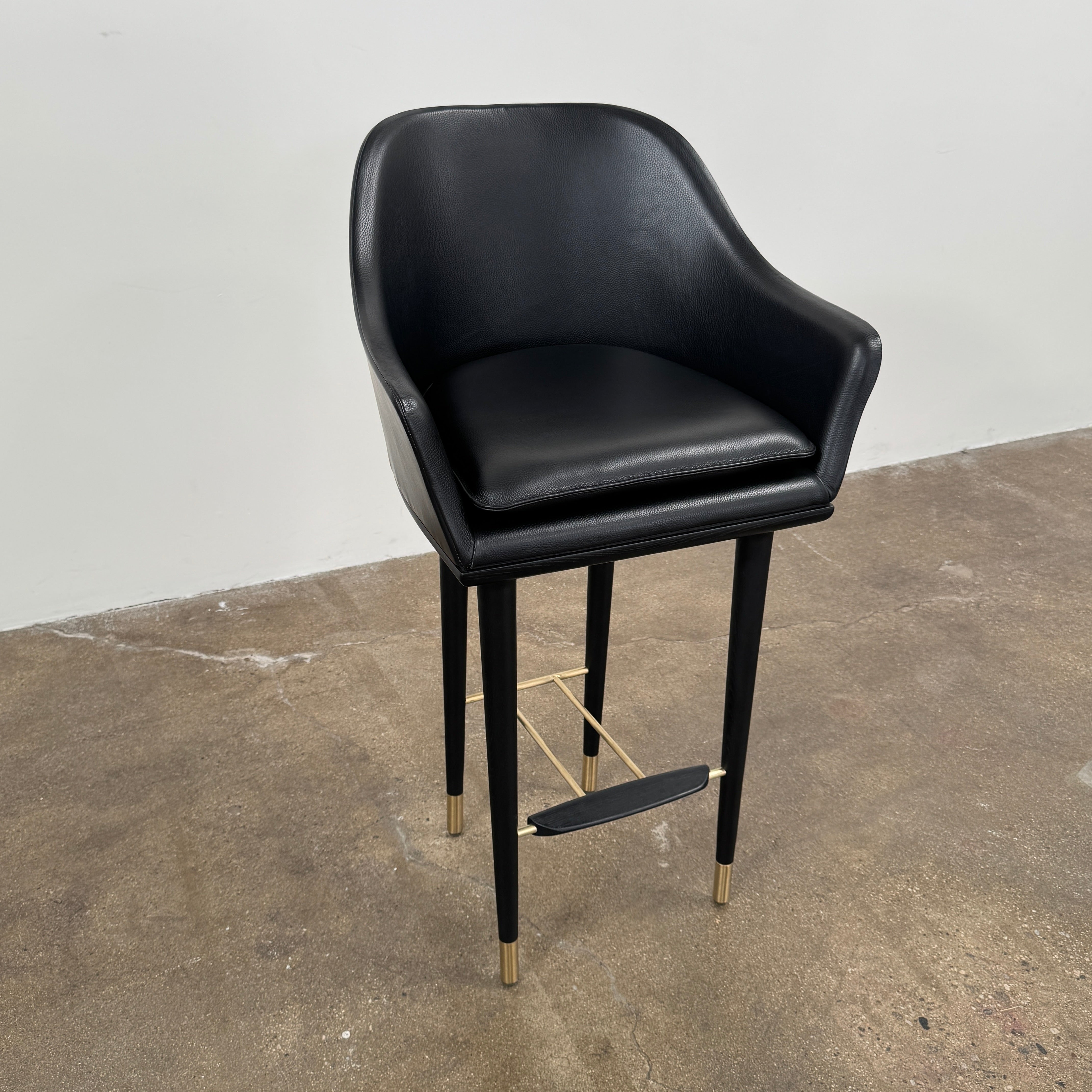 A set of three Stellar Works Lunar Bar Chairs by Steller Works, featuring black leather upholstery, armrests, and gold accents, is arranged in a row against a plain white background.