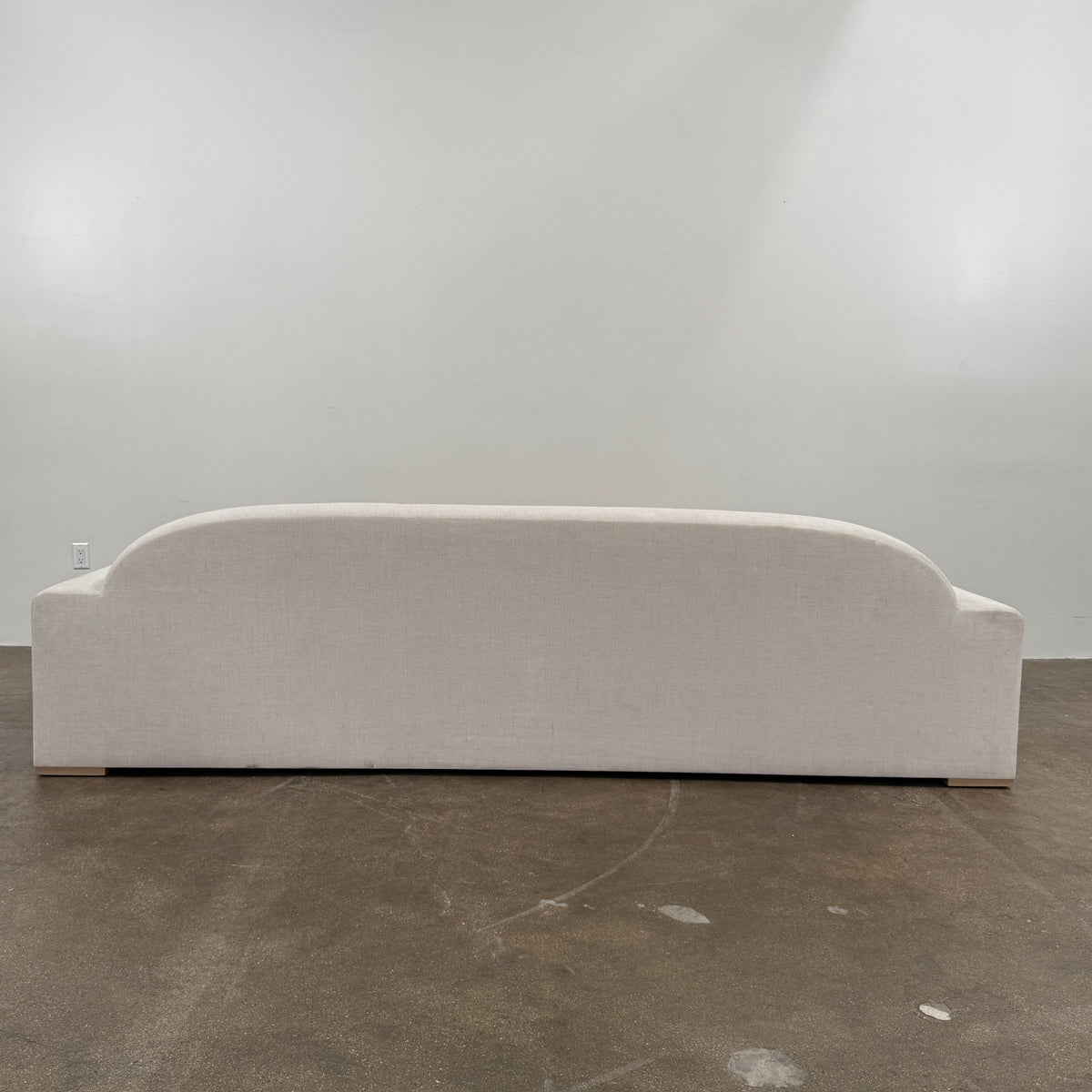 The Dmitriy & Co. Erato Sofa by Dimitriy & Co is a light gray three-seater featuring low arms and wooden feet, showcased against a plain white background—an elegant example of bespoke furnishings and couture upholstery.