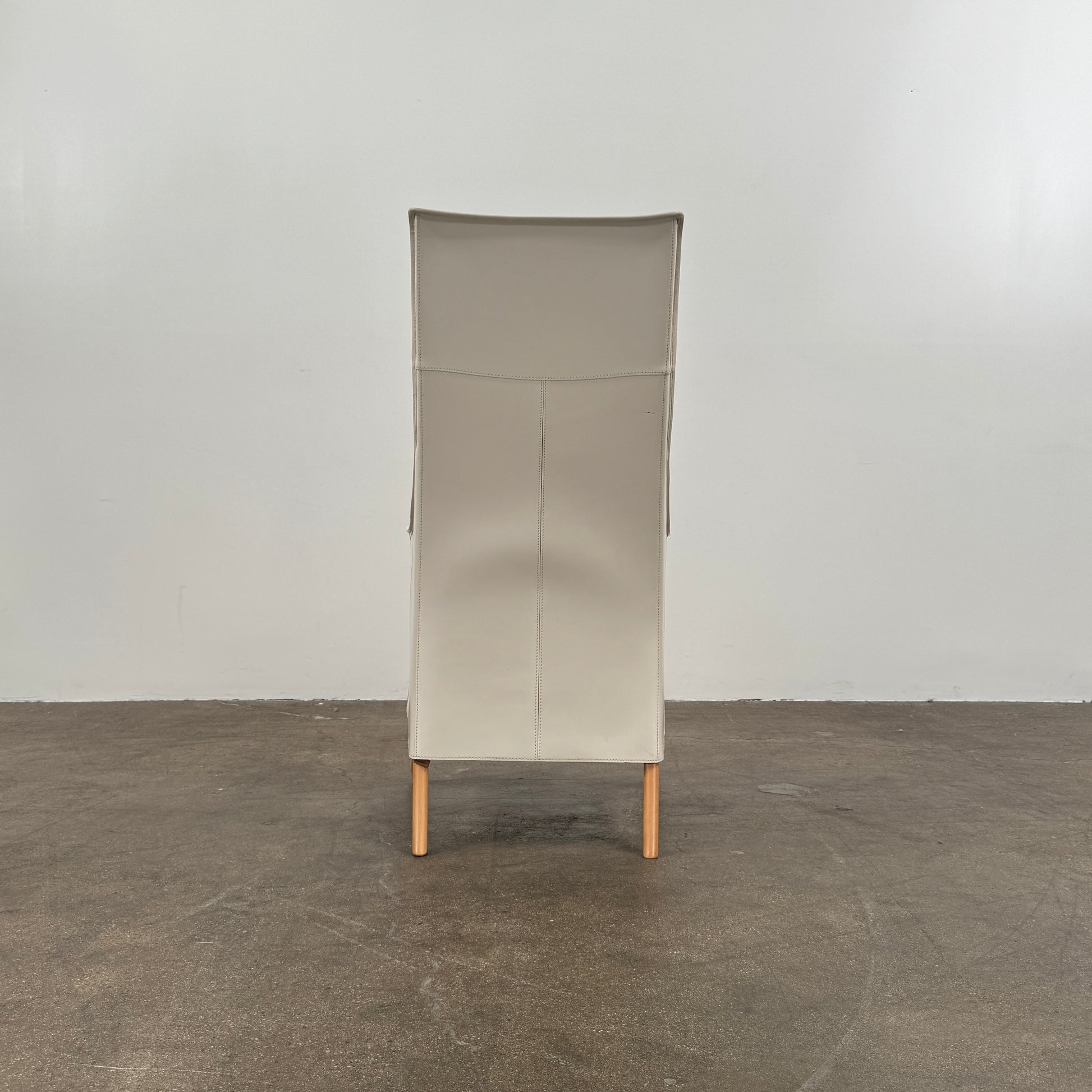 The Giorgetti “Progetti” Bergère / High-Back Lounge Chair by Giorgetti features light beige upholstery, wooden armrests and legs, and elegant ivory saddle leather accents, all inspired by the sophisticated Progetti collection, and is showcased against a plain white background.