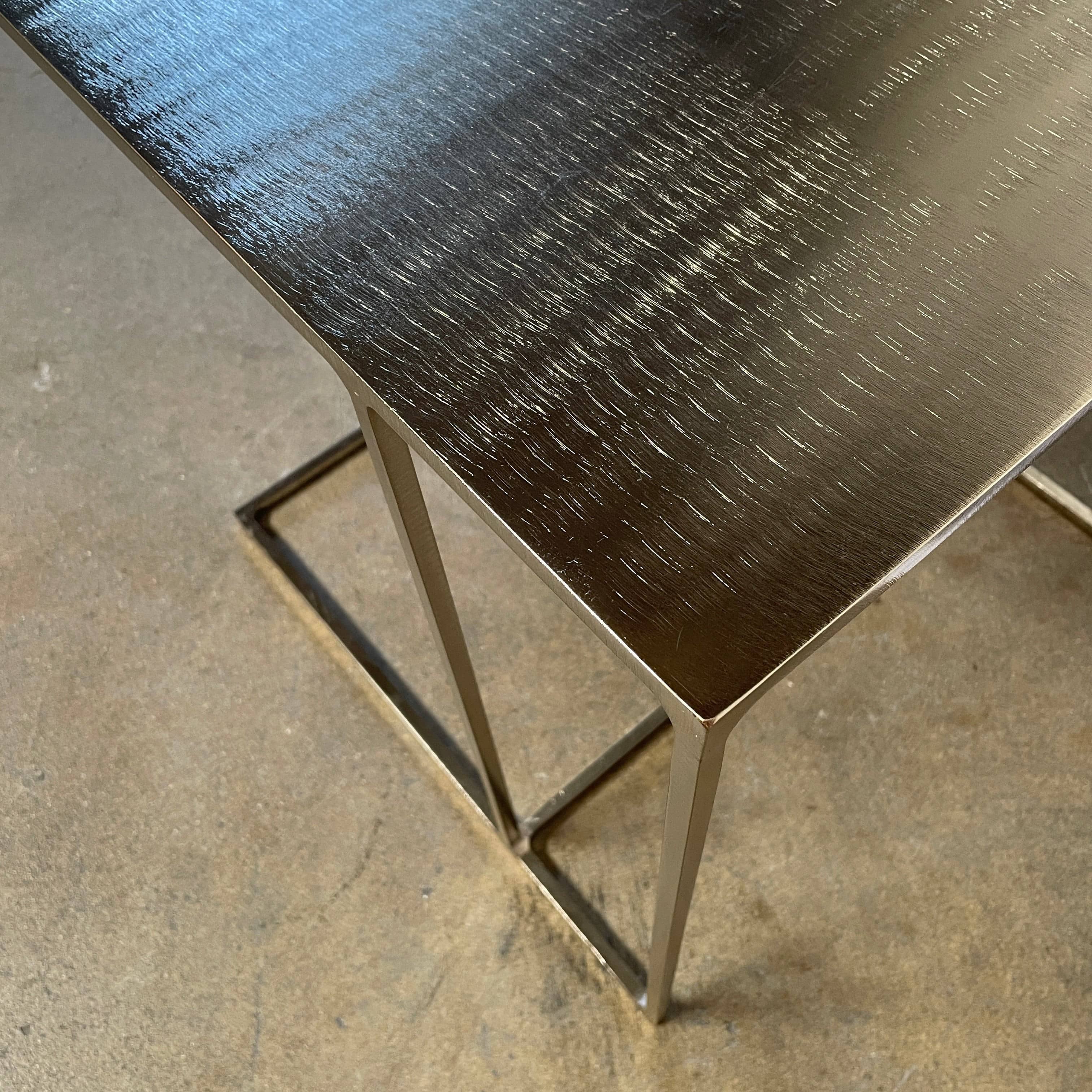 The Minotti Leger Side Table, by Minotti, features a metallic accent with its metal frame, creating a clean and minimal design against a white background.