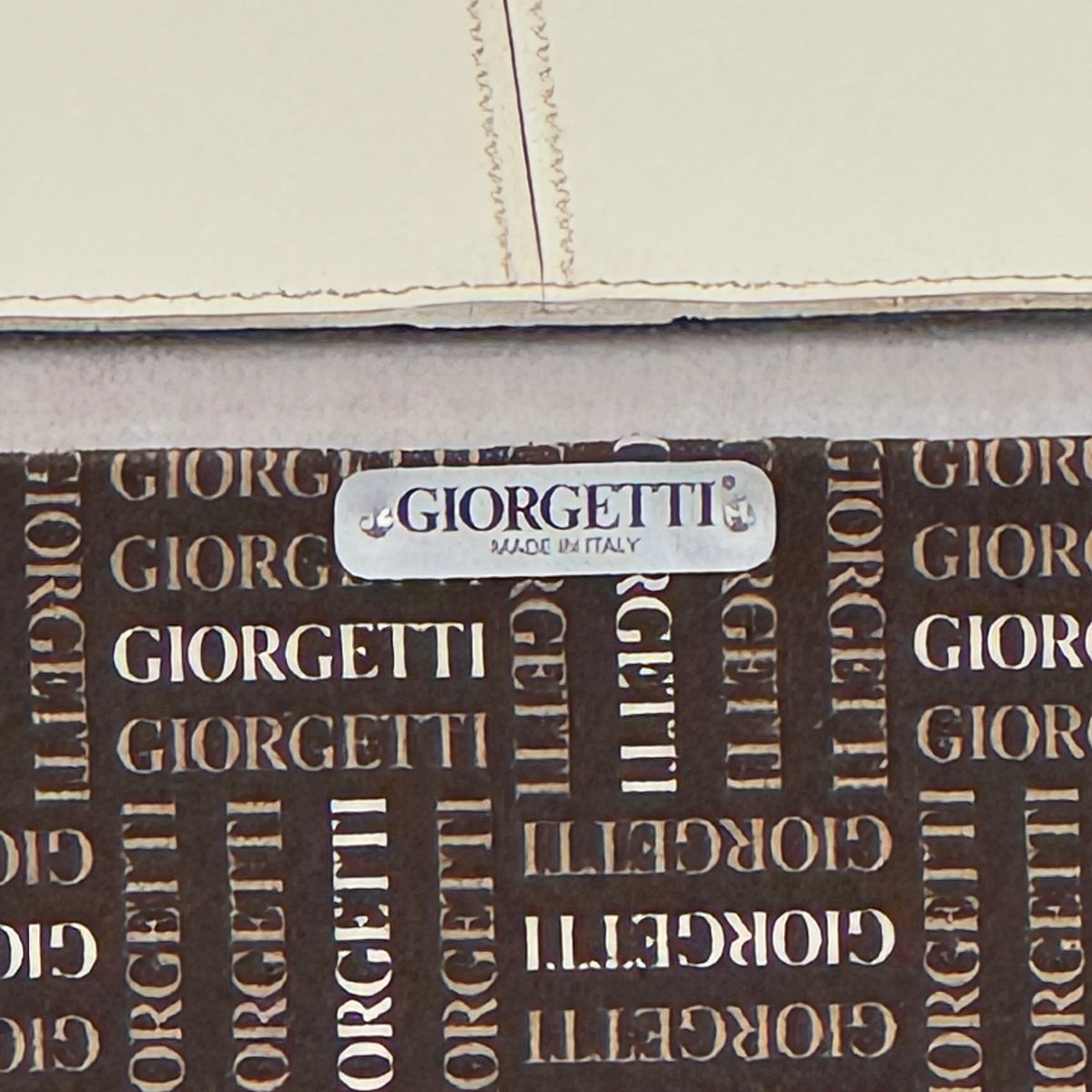 The Giorgetti “Progetti” Bergère / High-Back Lounge Chair by Giorgetti features light beige upholstery, wooden armrests and legs, and elegant ivory saddle leather accents, all inspired by the sophisticated Progetti collection, and is showcased against a plain white background.