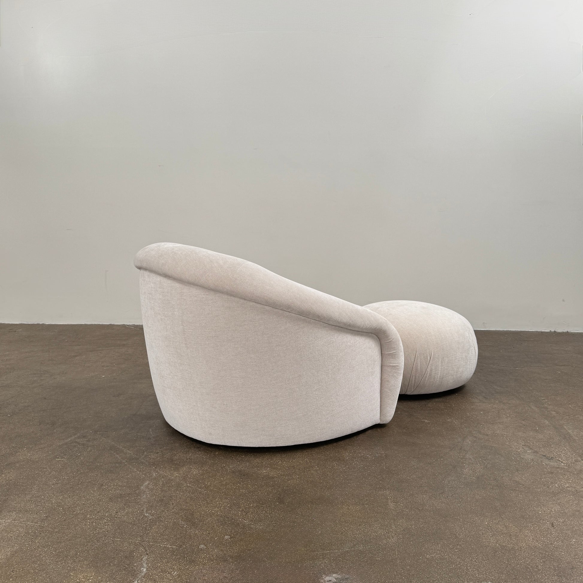 Certainly! Here’s a rewritten version of the sentence using your product data: The Vintage Chair + Ottoman – In The Style of Steve Chase by Vintage, featuring beige upholstery with rounded edges and a matching oval ottoman, both set against a plain white background, evoke the timeless elegance of mid-century modern furniture.