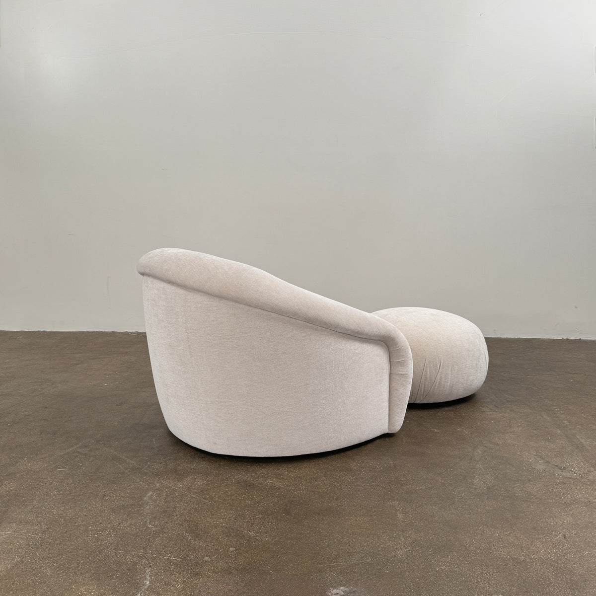 Certainly! Here’s a rewritten version of the sentence using your product data: The Vintage Chair + Ottoman – In The Style of Steve Chase by Vintage, featuring beige upholstery with rounded edges and a matching oval ottoman, both set against a plain white background, evoke the timeless elegance of mid-century modern furniture.