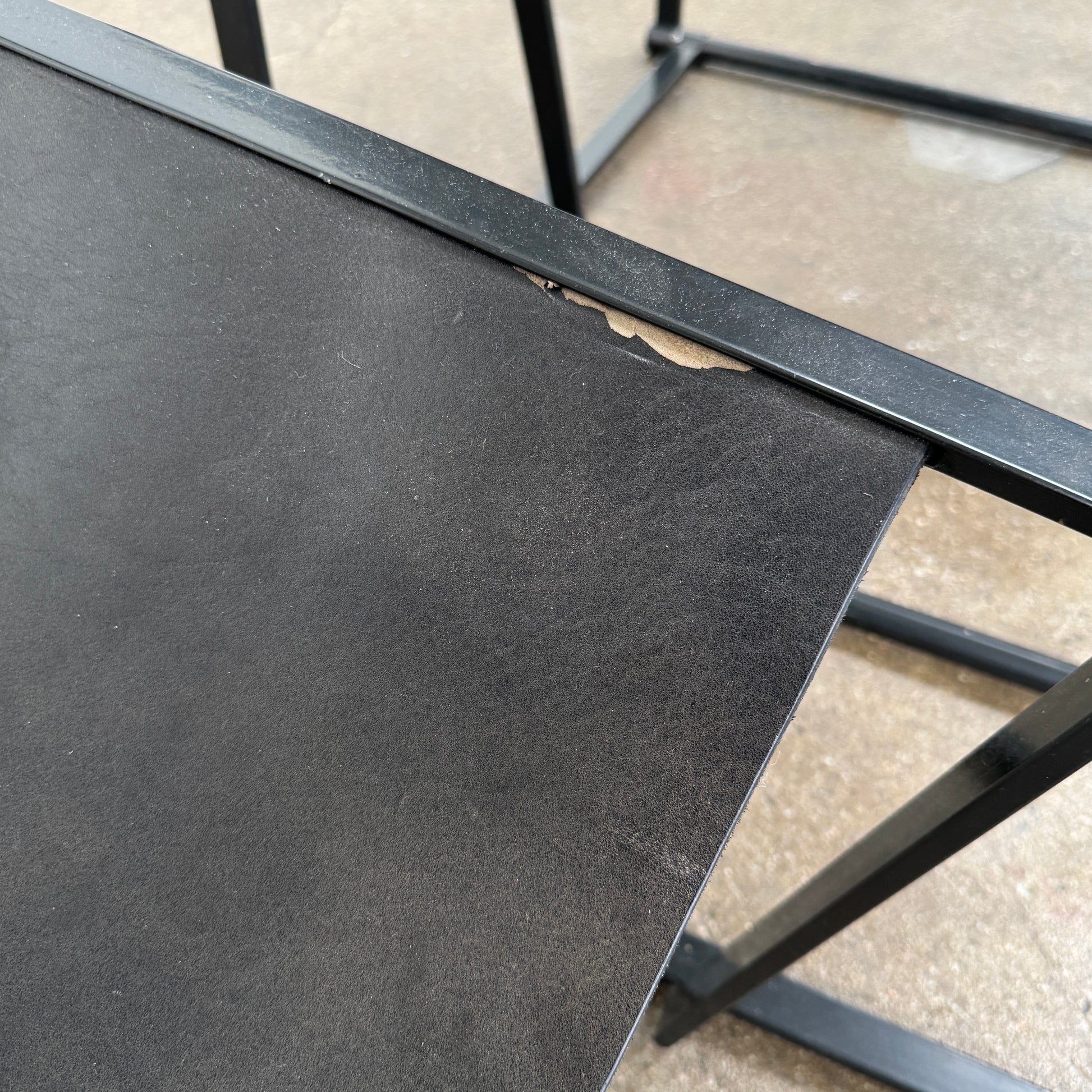 Two black Vintage Pastoe FM62 Chairs by Pastoe, inspired by constructivist design, are placed on a tile floor in a spacious, minimal living room with large windows overlooking a pool and greenery outside.