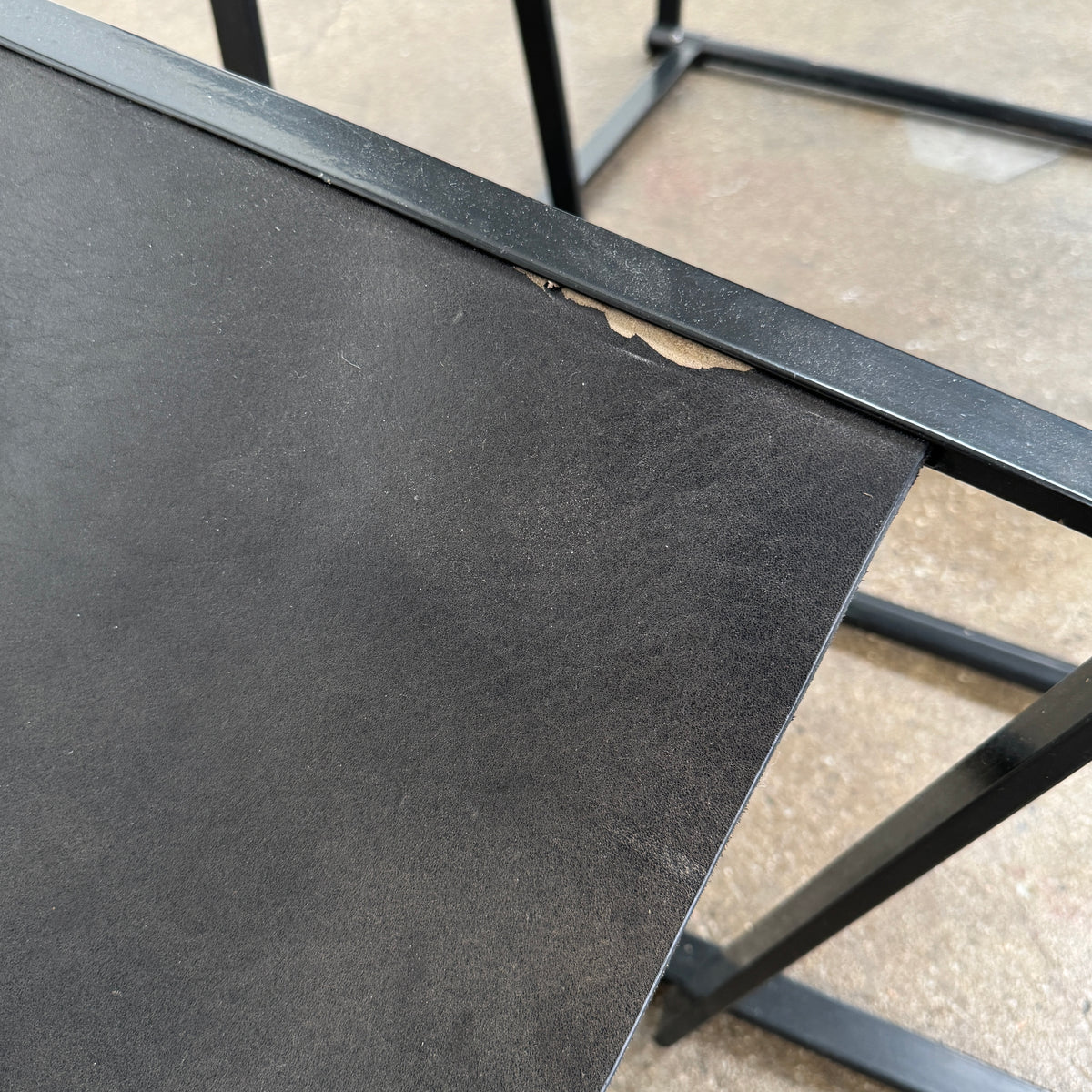 Two black Vintage Pastoe FM62 Chairs by Pastoe, inspired by constructivist design, are placed on a tile floor in a spacious, minimal living room with large windows overlooking a pool and greenery outside.