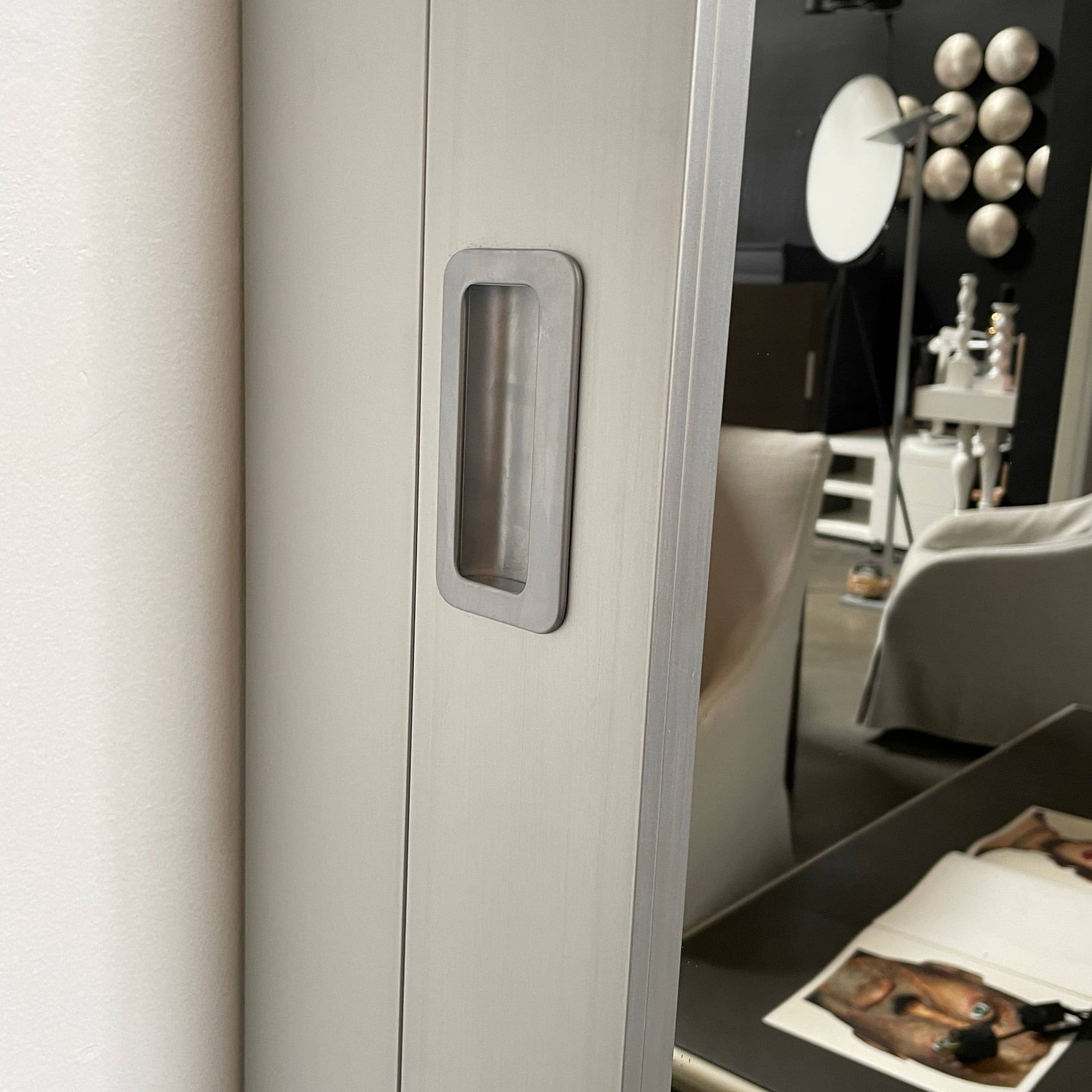 A Bellato Box Mirror Cabinet, featuring a rectangular, full-length design with a thin silver frame, stands elegantly against a plain light gray background.