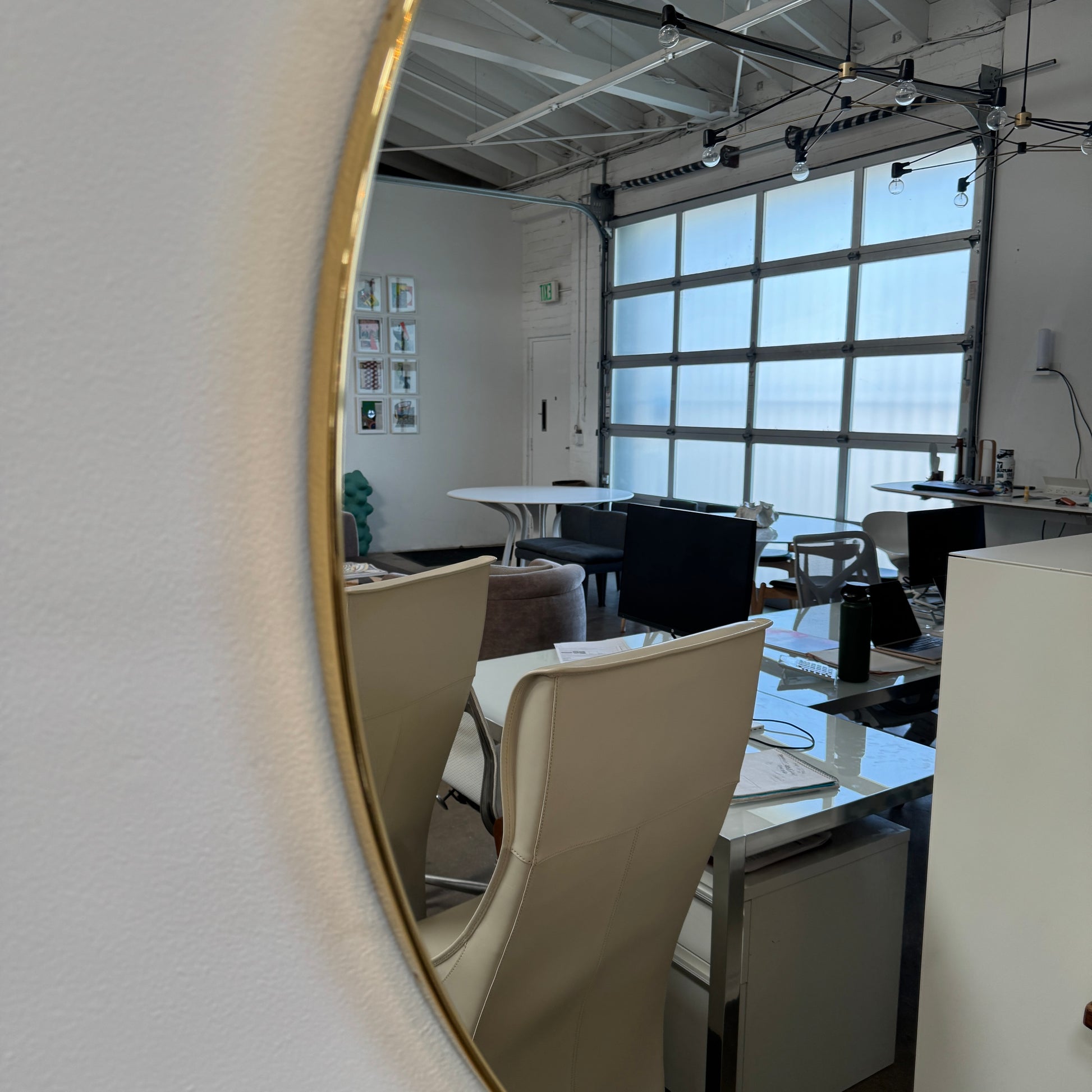The Gubi 43″ Round Wall Mirror in Polished Brass, by Gubi, is displayed against a plain light gray background, showcasing its sleek and timeless design inspired by the iconic Gubi wall mirror.