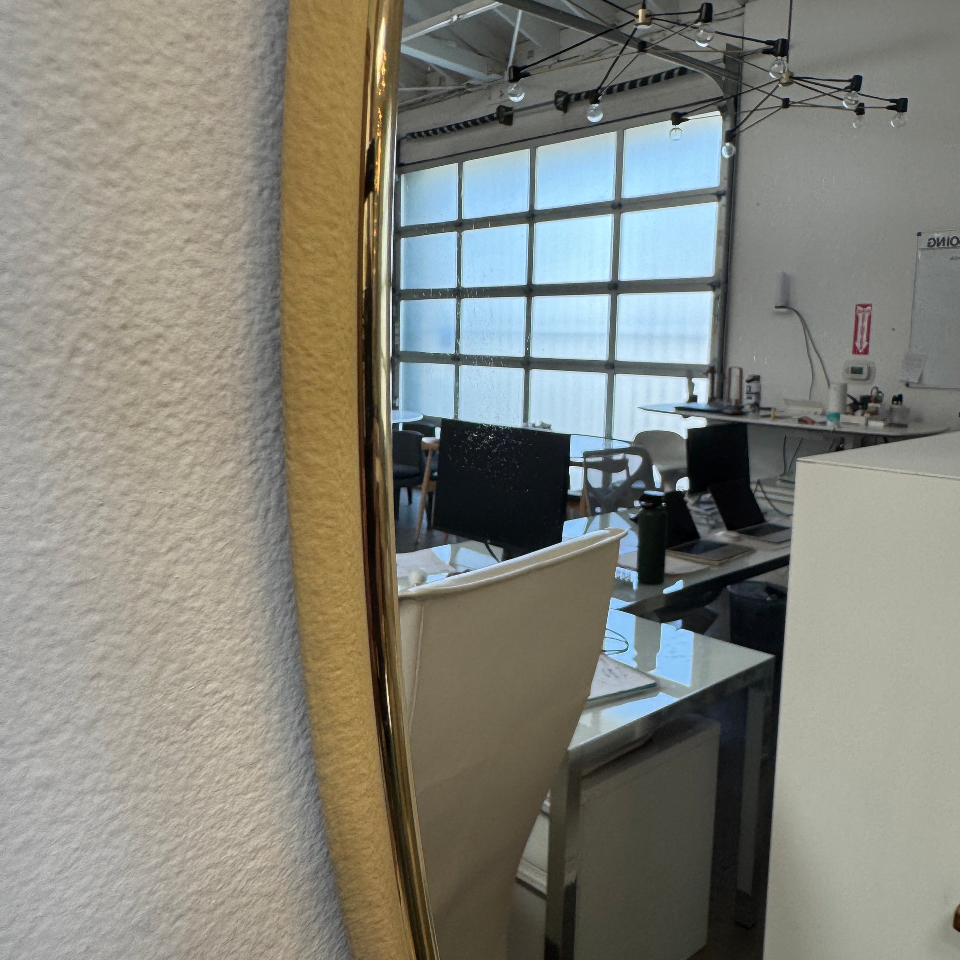 The Gubi 43″ Round Wall Mirror in Polished Brass, by Gubi, is displayed against a plain light gray background, showcasing its sleek and timeless design inspired by the iconic Gubi wall mirror.