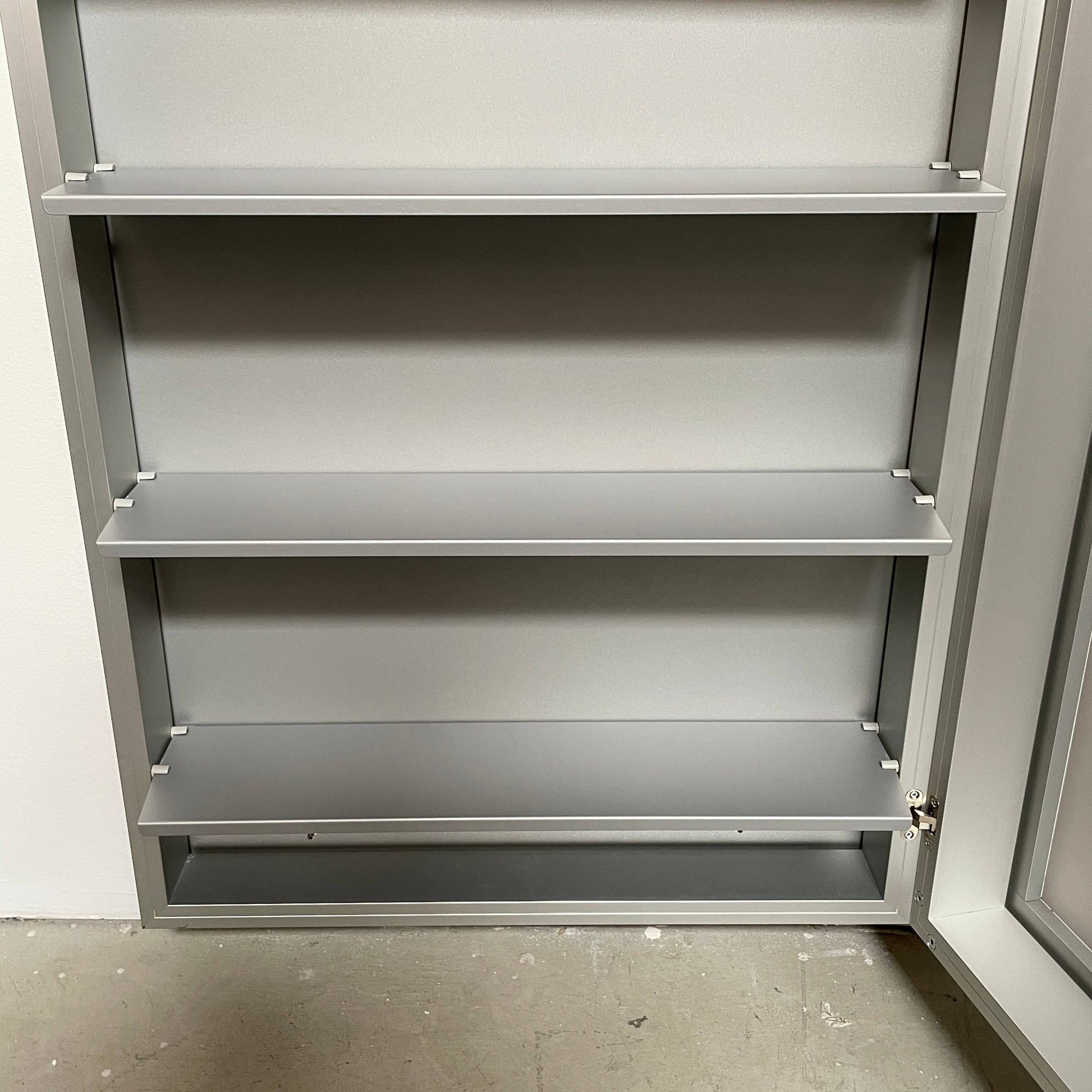 A Bellato Box Mirror Cabinet, featuring a rectangular, full-length design with a thin silver frame, stands elegantly against a plain light gray background.