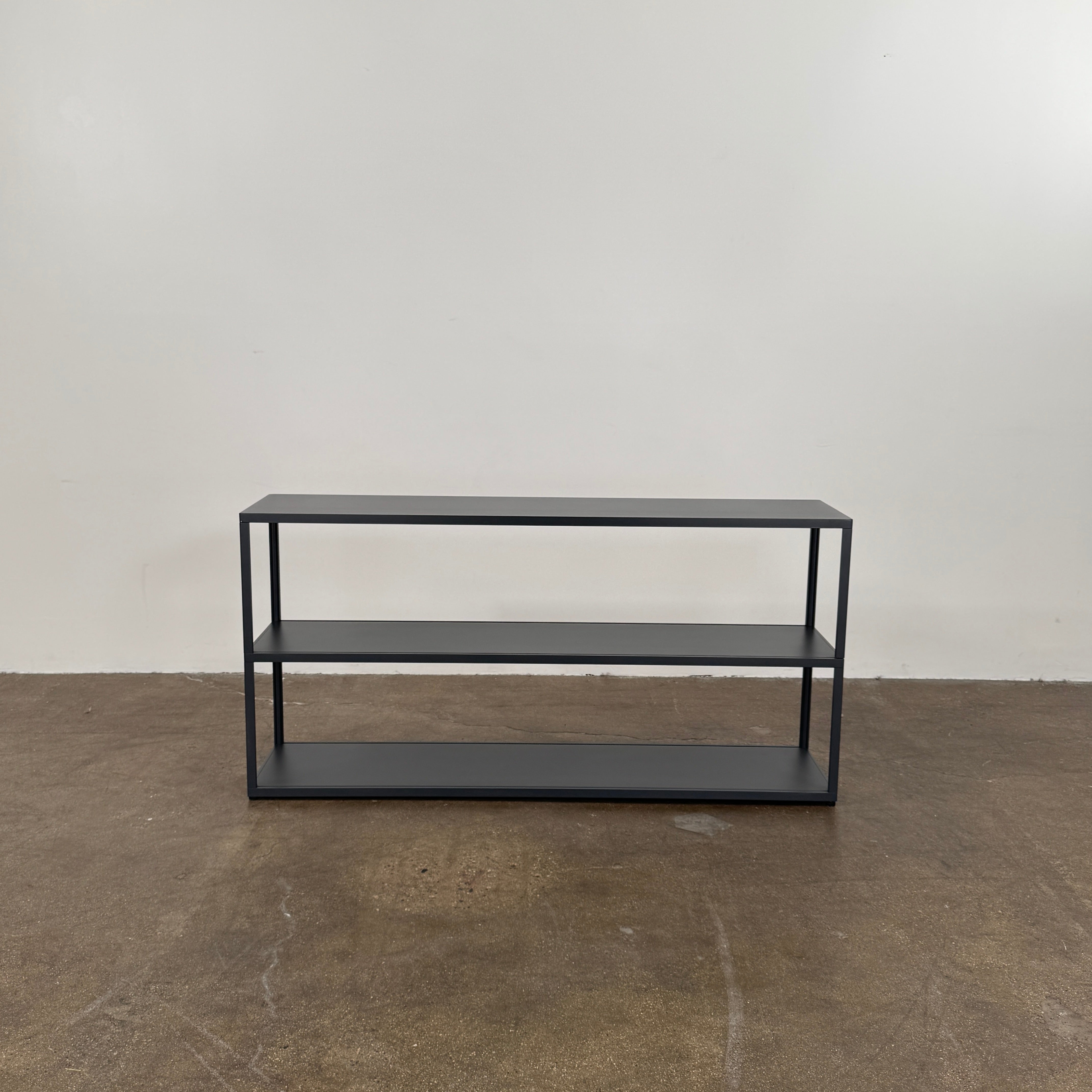 The Hay New Order System Shelves by Hay is a black, metal-framed, two-shelf open bookcase featuring a minimalist design inspired by Scandinavian aesthetics, shown against a plain white background.