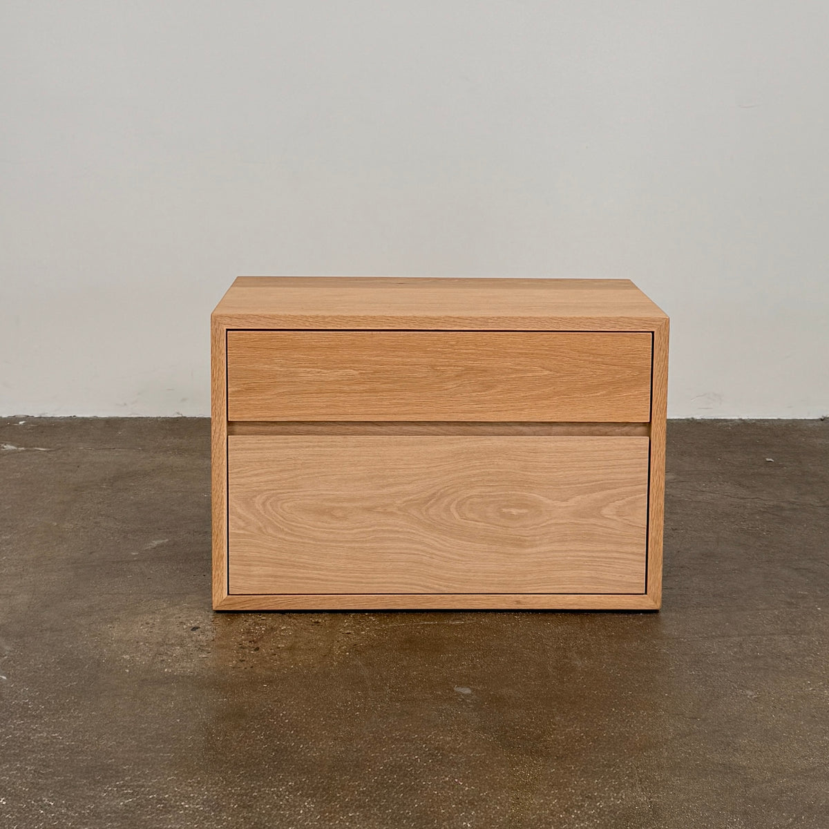 The Jenni Kayne Palms Nightstand Oak 30” by Jenni Kayne is a rectangular wooden drawer unit with a minimalist design, featuring one large lower drawer and one smaller upper drawer, showcased against a plain white background—a piece that perfectly captures the understated elegance of an oak nightstand, making it an ideal choice as a refined bedside table.