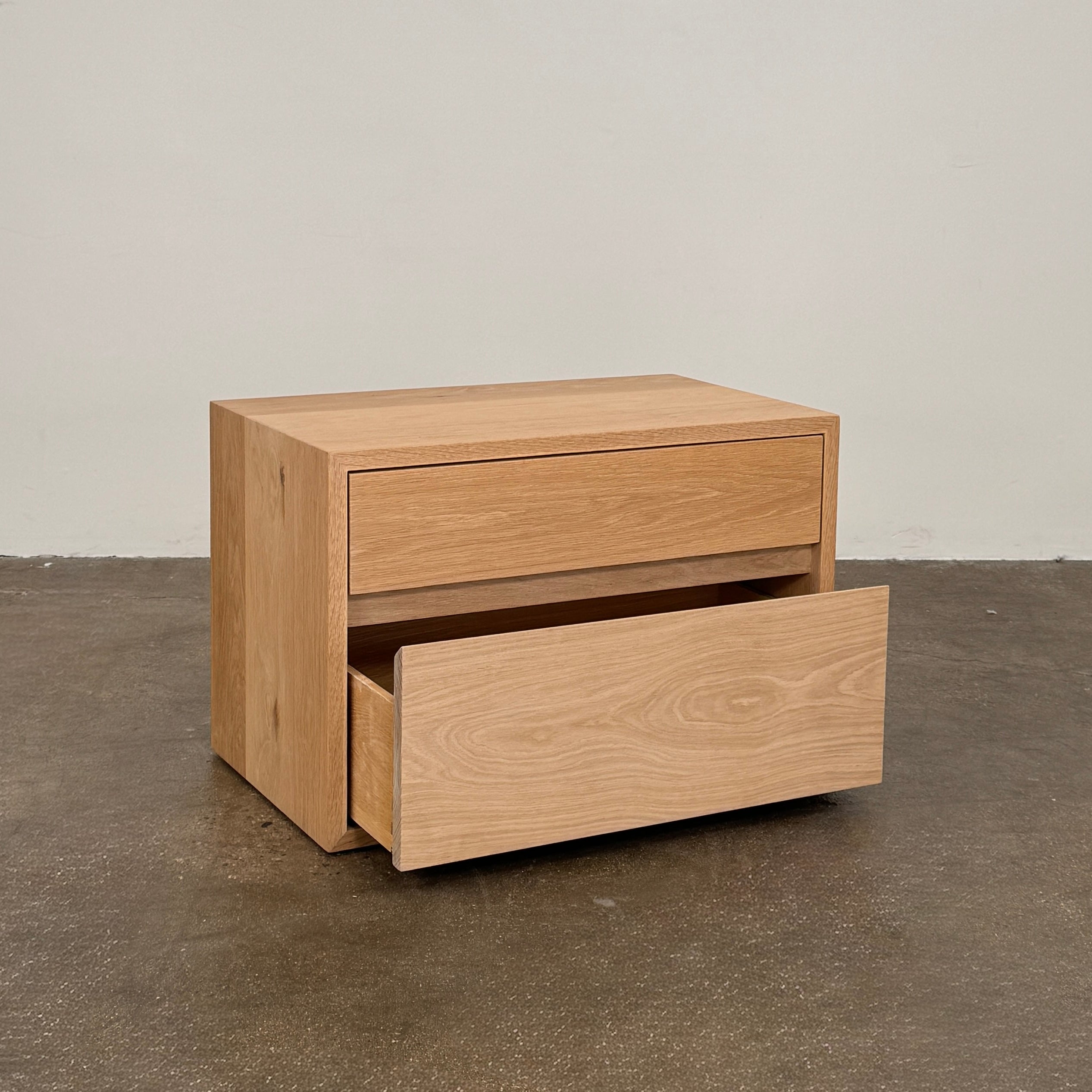 The Jenni Kayne Palms Nightstand Oak 30” by Jenni Kayne is a rectangular wooden drawer unit with a minimalist design, featuring one large lower drawer and one smaller upper drawer, showcased against a plain white background—a piece that perfectly captures the understated elegance of an oak nightstand, making it an ideal choice as a refined bedside table.