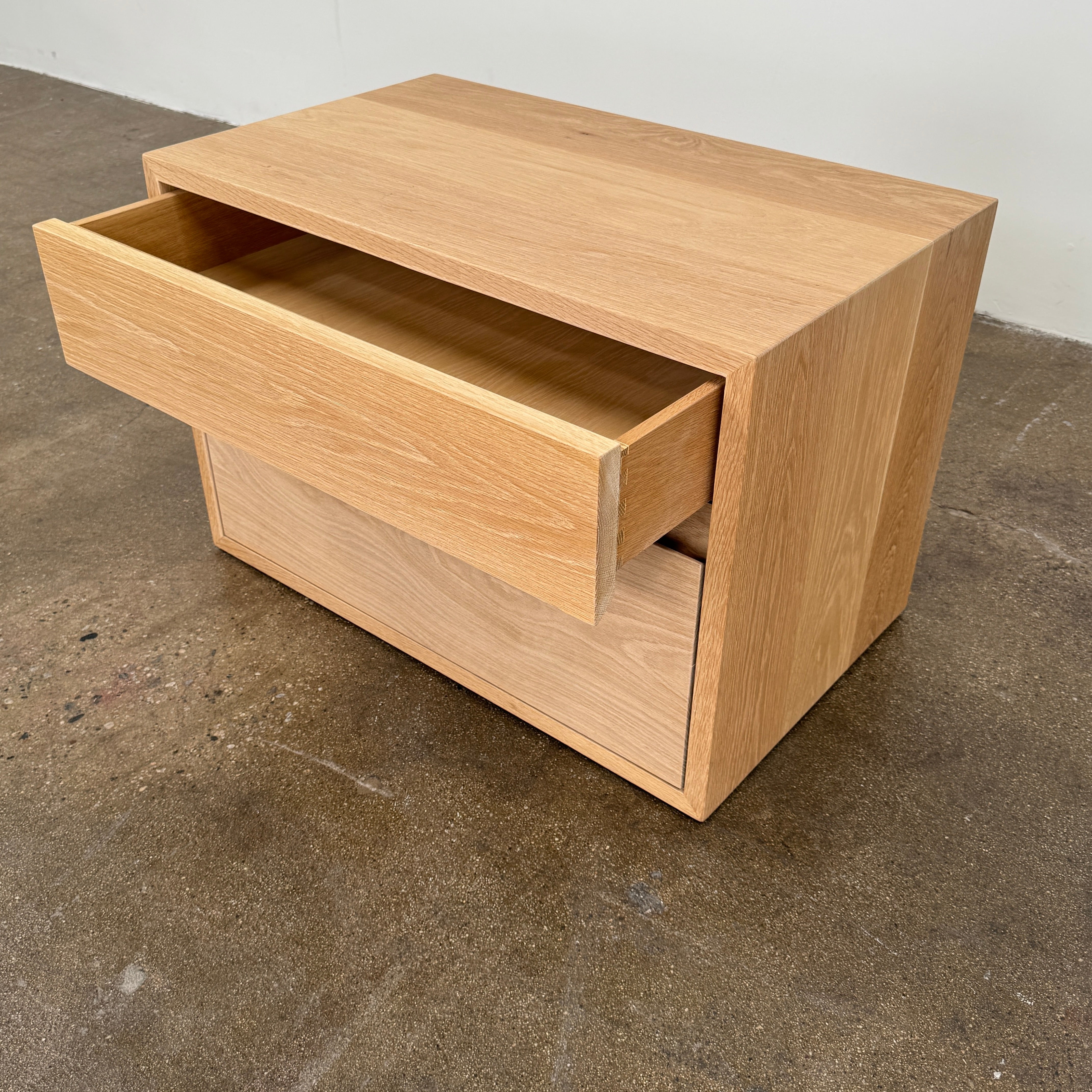 The Jenni Kayne Palms Nightstand Oak 30” by Jenni Kayne is a rectangular wooden drawer unit with a minimalist design, featuring one large lower drawer and one smaller upper drawer, showcased against a plain white background—a piece that perfectly captures the understated elegance of an oak nightstand, making it an ideal choice as a refined bedside table.
