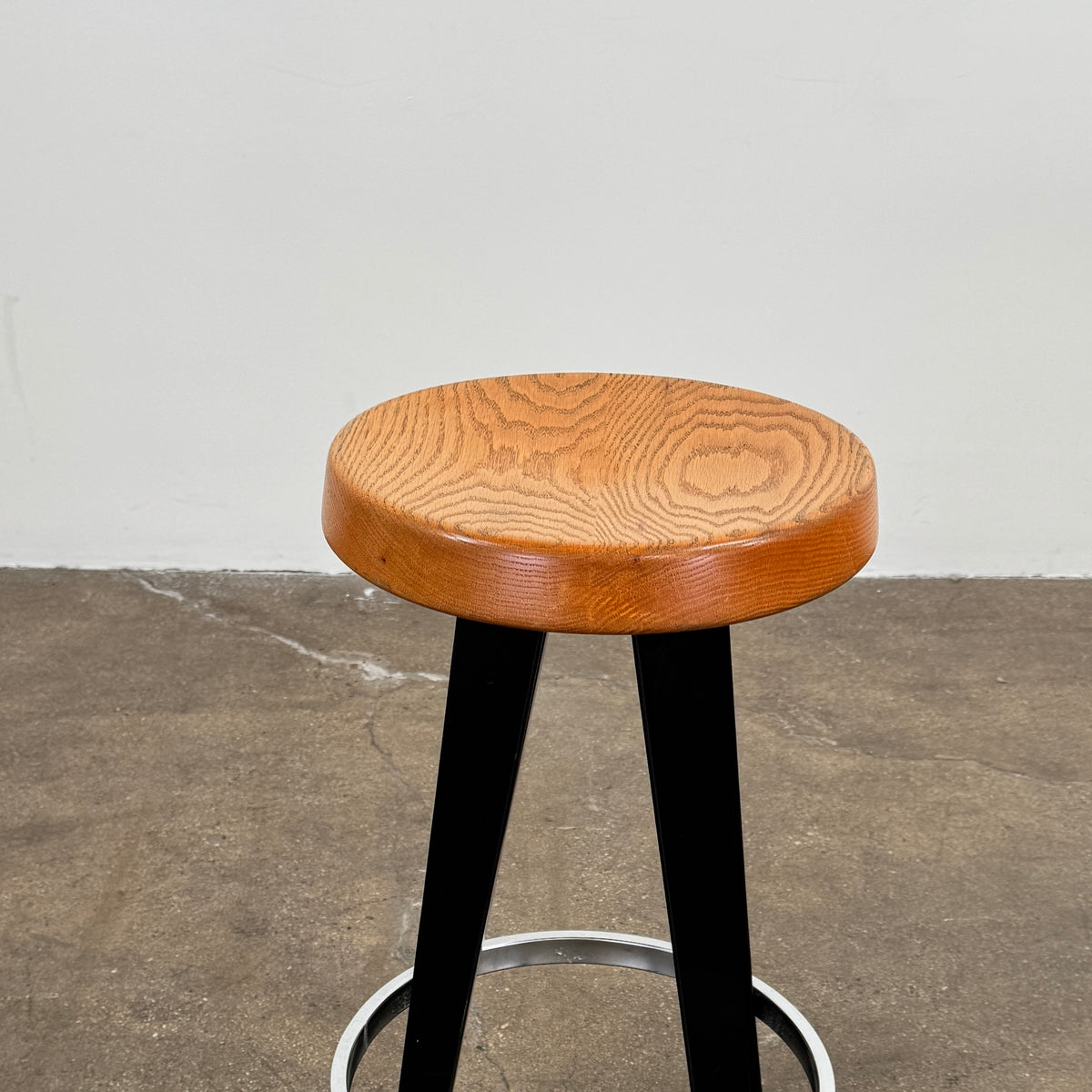 A set of three Vintage Stools in the style of Jean Prouve by Vintage, featuring black metal frames, round brown wooden seats, and silver footrests, are arranged in a row against a plain white background, evoking a classic mid-century design.
