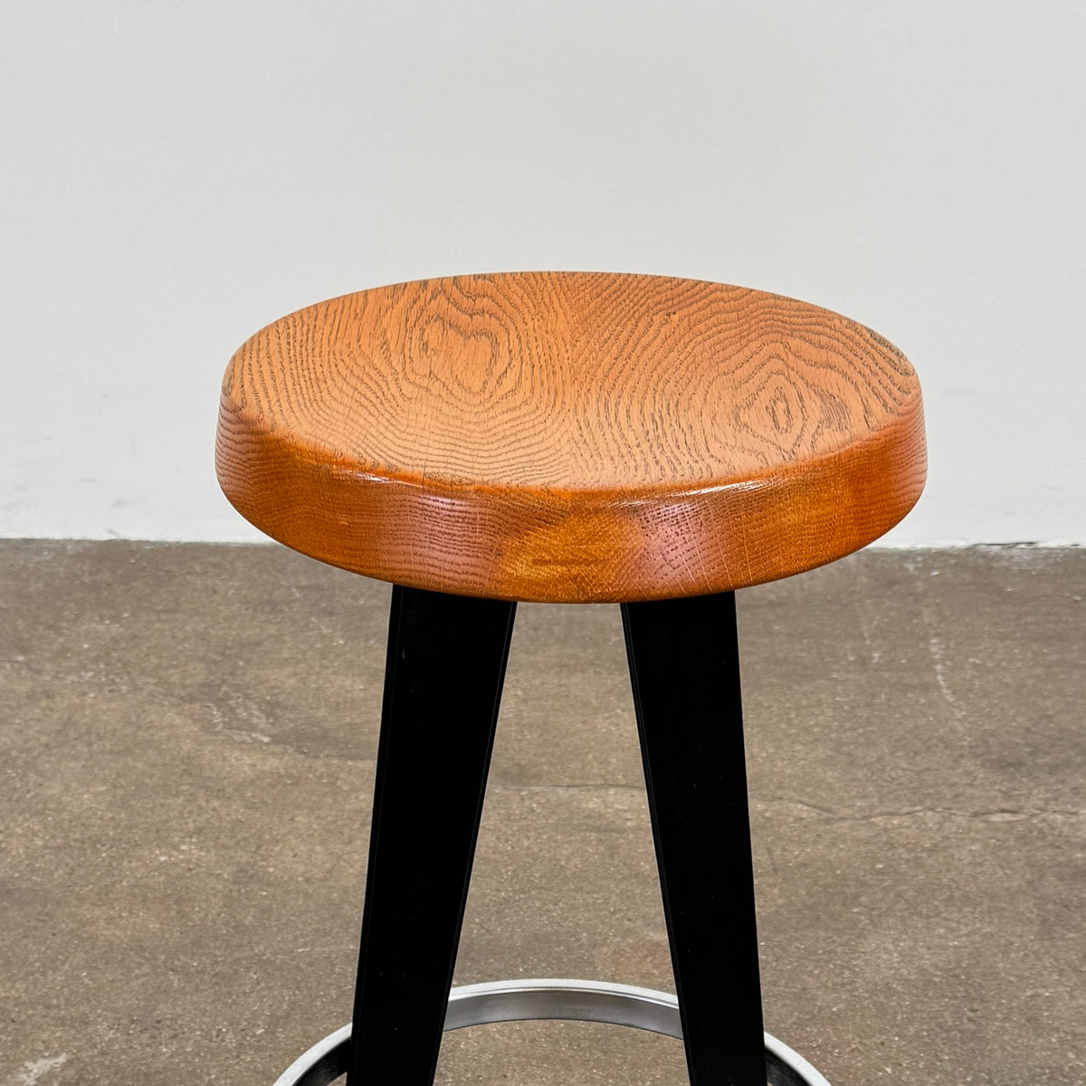 A set of three Vintage Stools in the style of Jean Prouve by Vintage, featuring black metal frames, round brown wooden seats, and silver footrests, are arranged in a row against a plain white background, evoking a classic mid-century design.