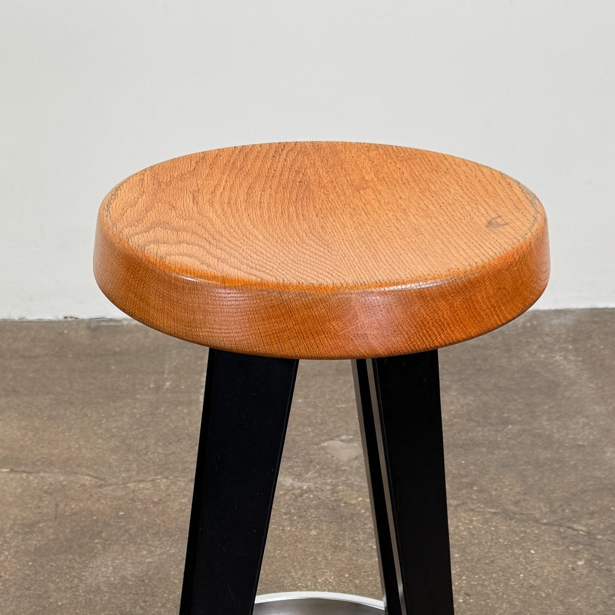 A set of three Vintage Stools in the style of Jean Prouve by Vintage, featuring black metal frames, round brown wooden seats, and silver footrests, are arranged in a row against a plain white background, evoking a classic mid-century design.