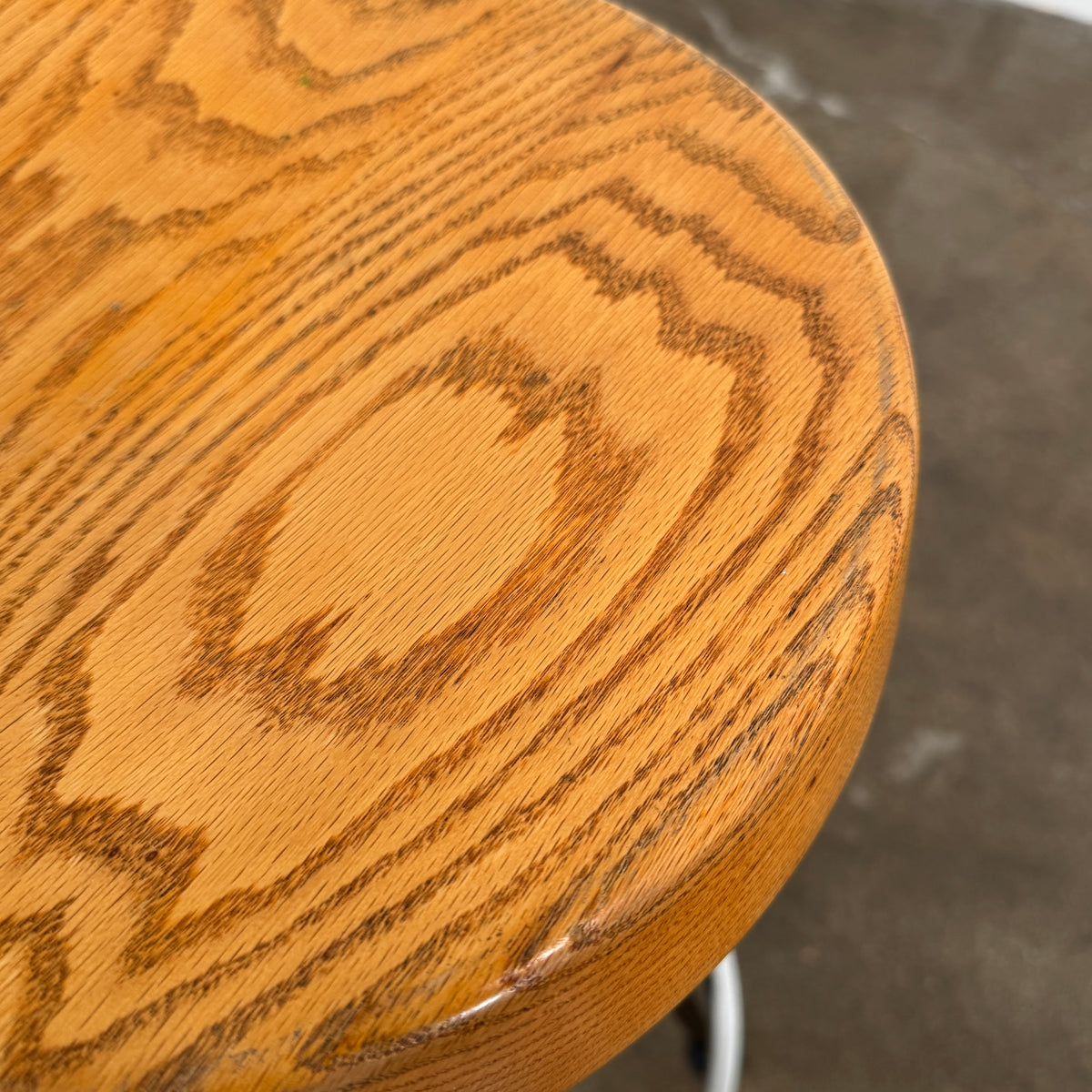 A set of three Vintage Stools in the style of Jean Prouve by Vintage, featuring black metal frames, round brown wooden seats, and silver footrests, are arranged in a row against a plain white background, evoking a classic mid-century design.