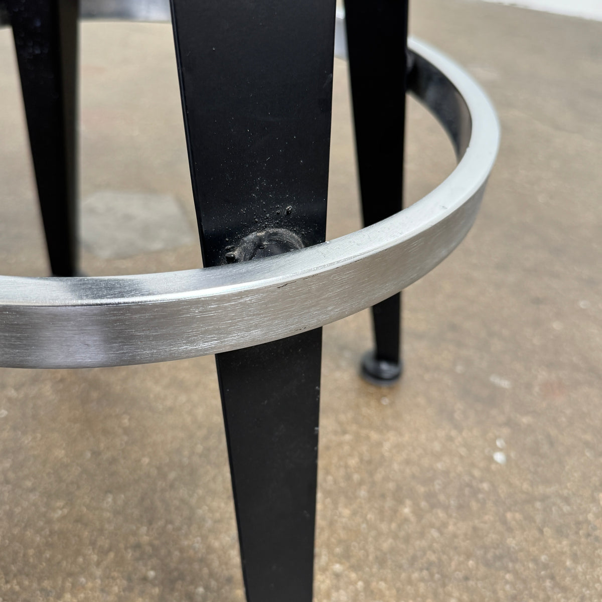 A set of three Vintage Stools in the style of Jean Prouve by Vintage, featuring black metal frames, round brown wooden seats, and silver footrests, are arranged in a row against a plain white background, evoking a classic mid-century design.