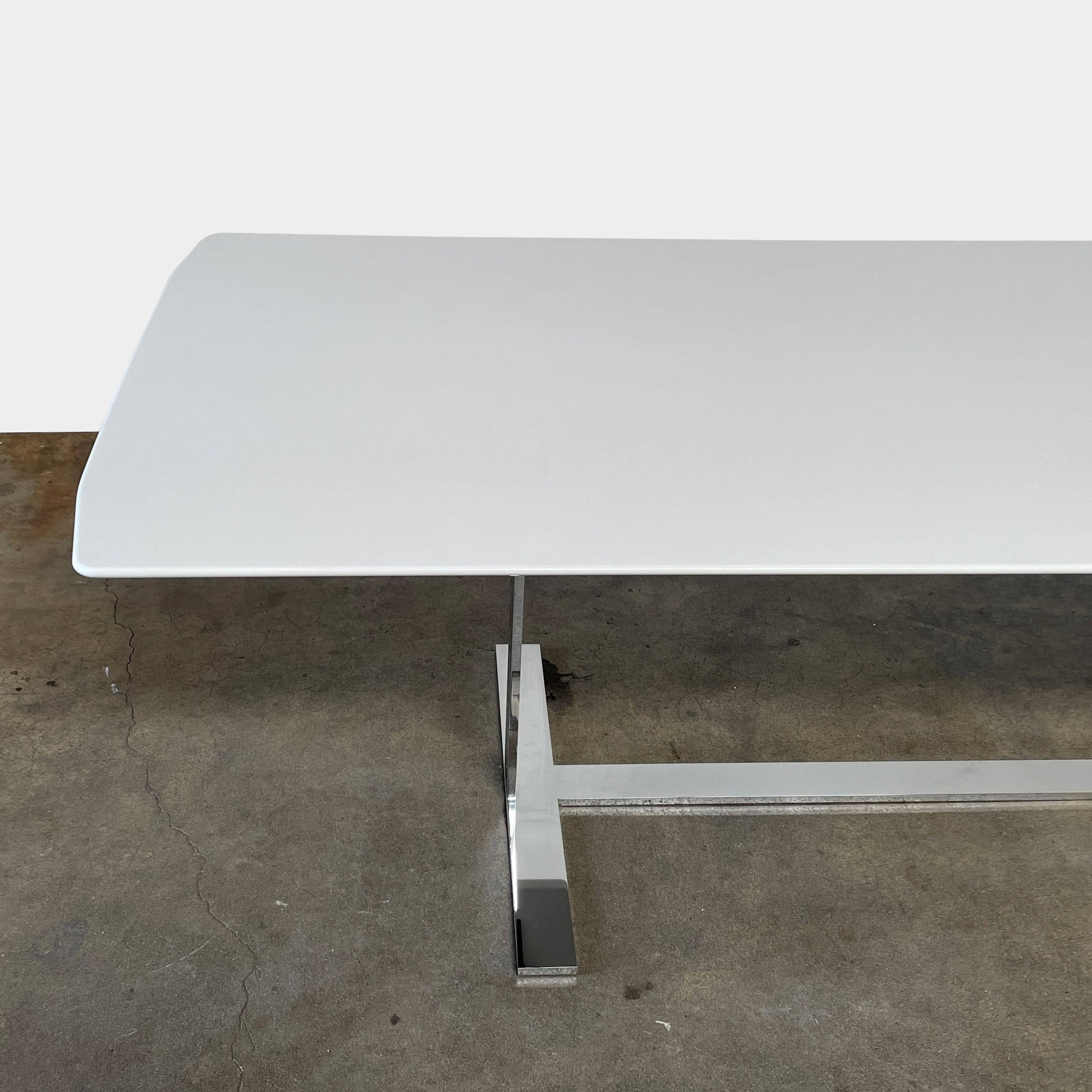 A minimalist rectangular B&B Italia Eileen White Dining Table featuring a sophisticated T-shaped metal base on a plain white background.