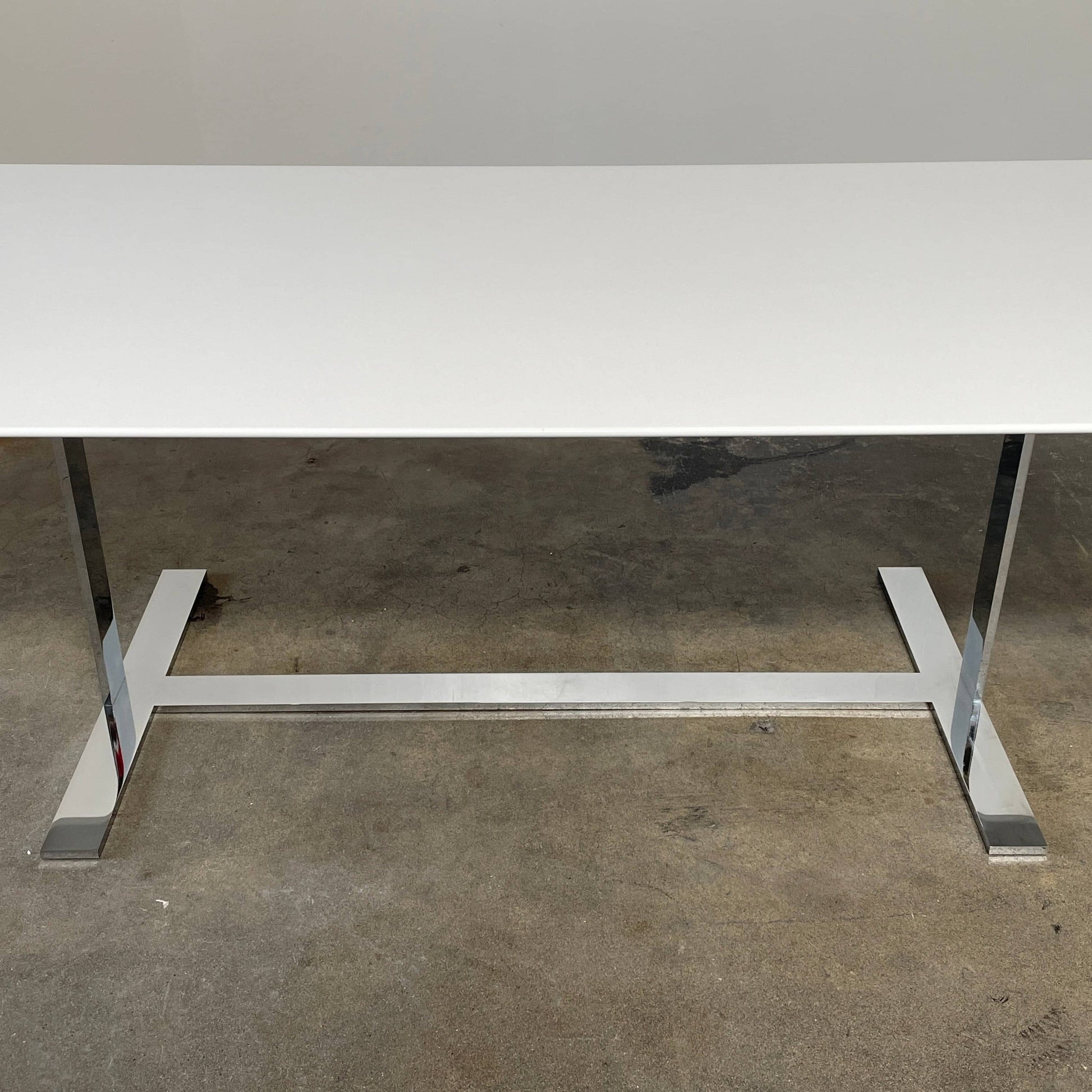 A minimalist rectangular B&B Italia Eileen White Dining Table featuring a sophisticated T-shaped metal base on a plain white background.