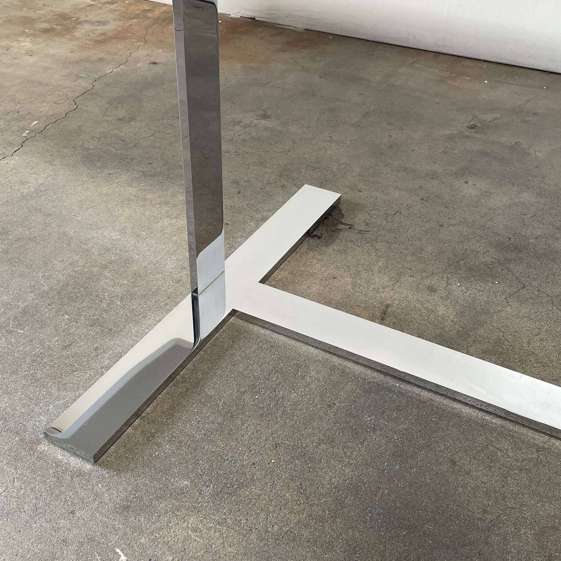 A minimalist rectangular B&B Italia Eileen White Dining Table featuring a sophisticated T-shaped metal base on a plain white background.