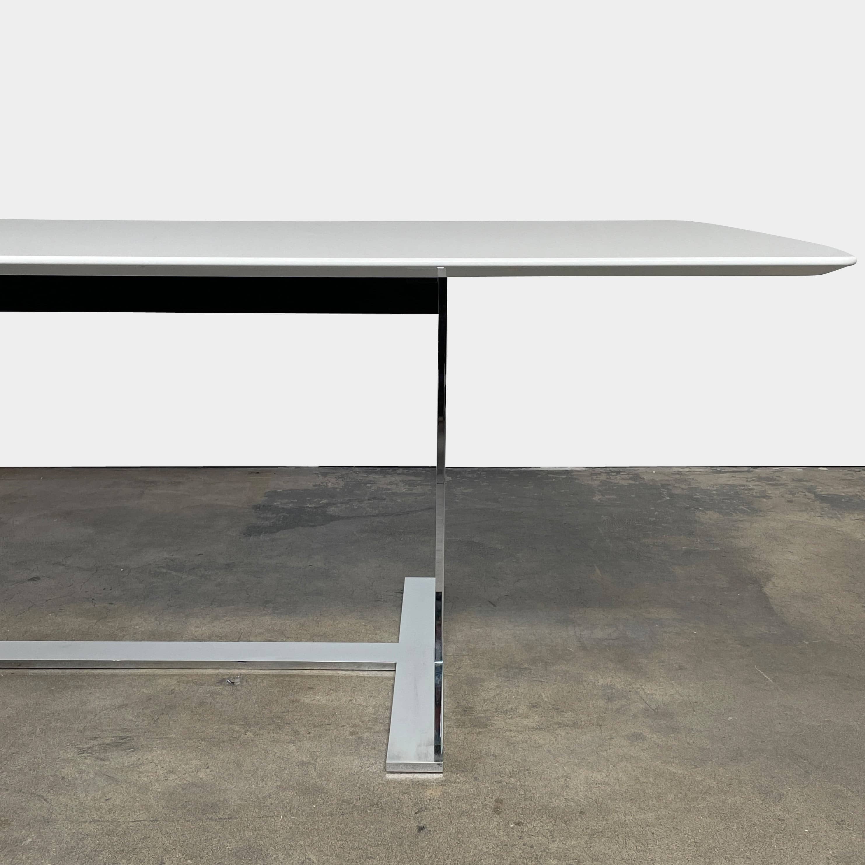 A minimalist rectangular B&B Italia Eileen White Dining Table featuring a sophisticated T-shaped metal base on a plain white background.