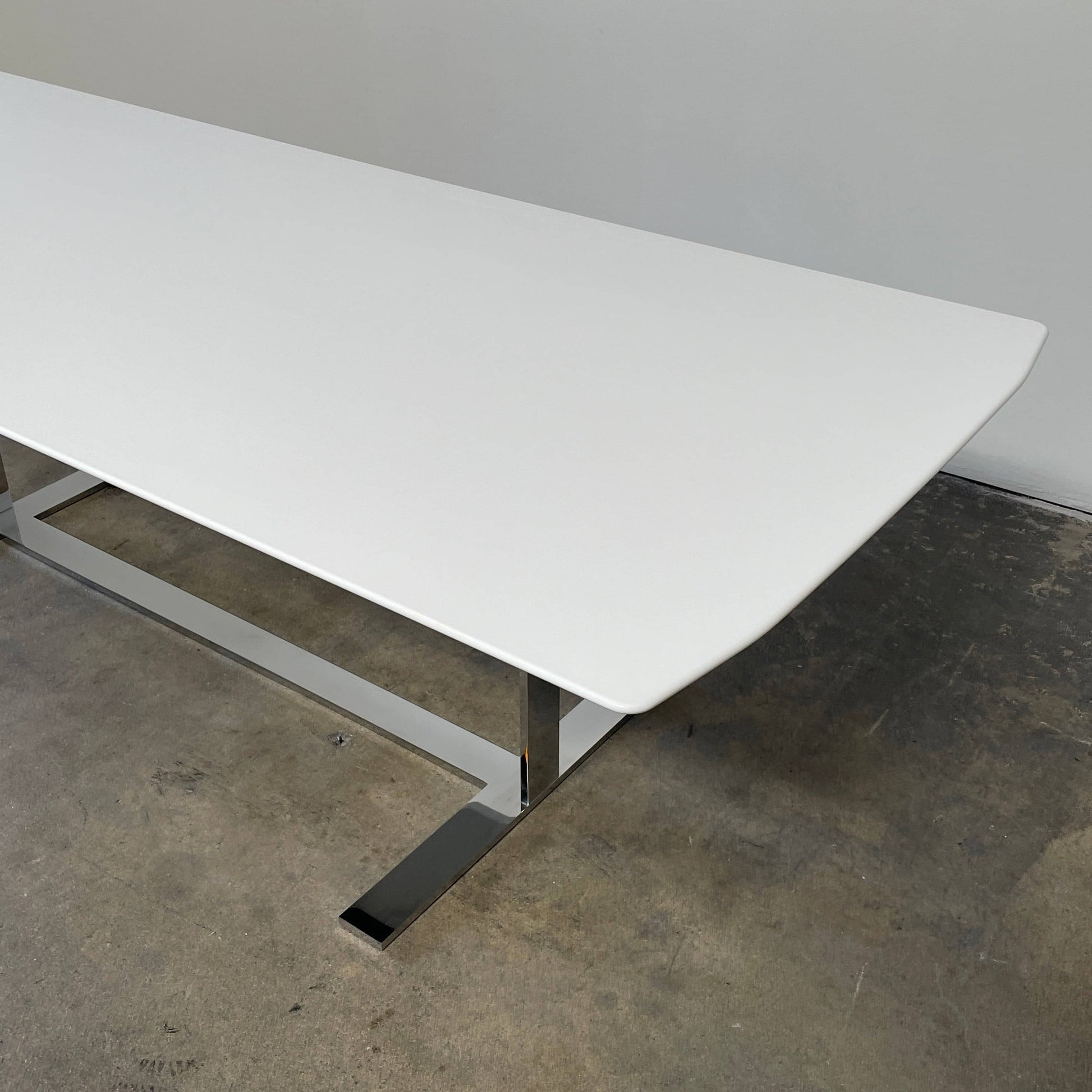 A minimalist rectangular B&B Italia Eileen White Dining Table featuring a sophisticated T-shaped metal base on a plain white background.