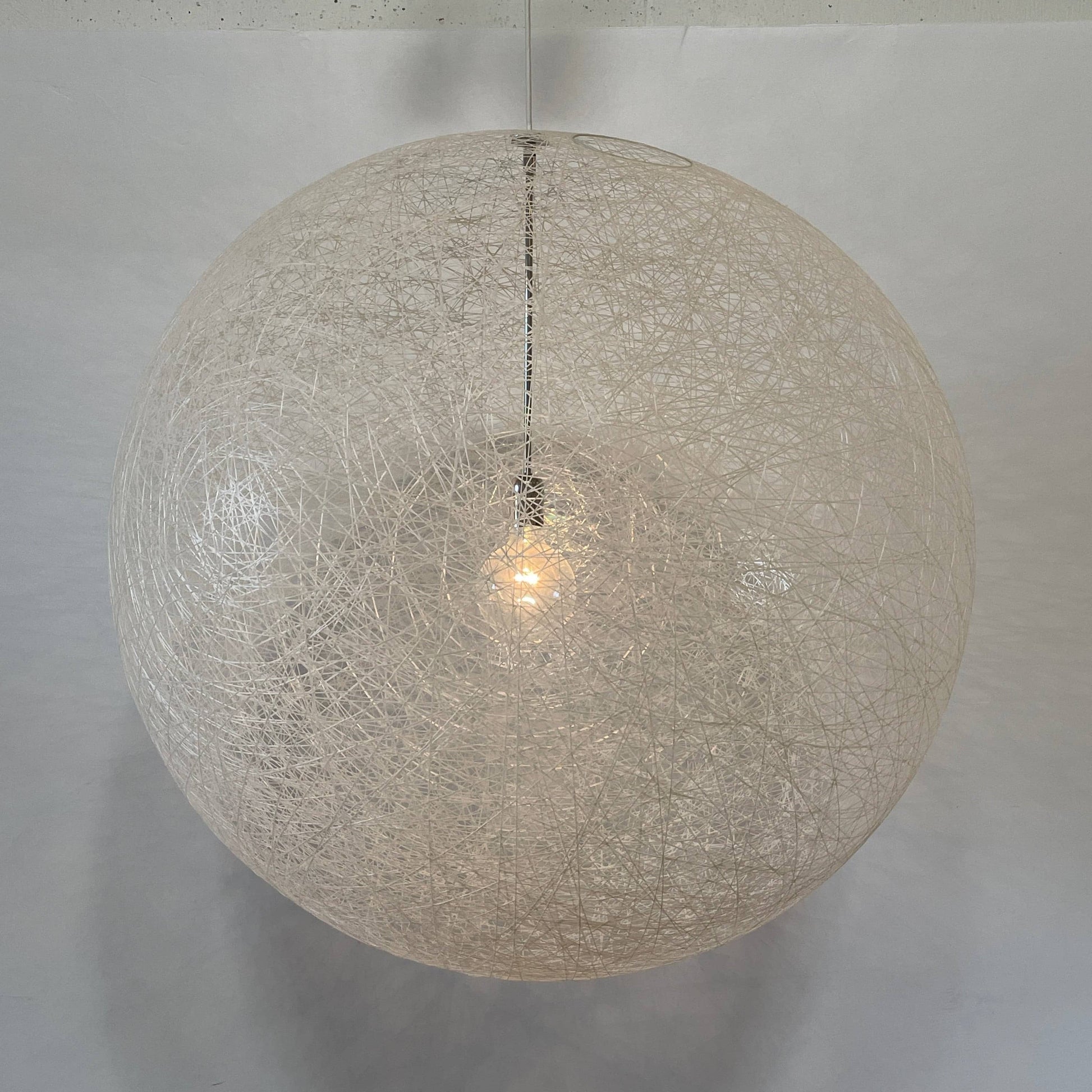 A Moooi Random Pendant suspension light with a white ball, reminiscent of the Moooi Random design, hanging from a light fixture.