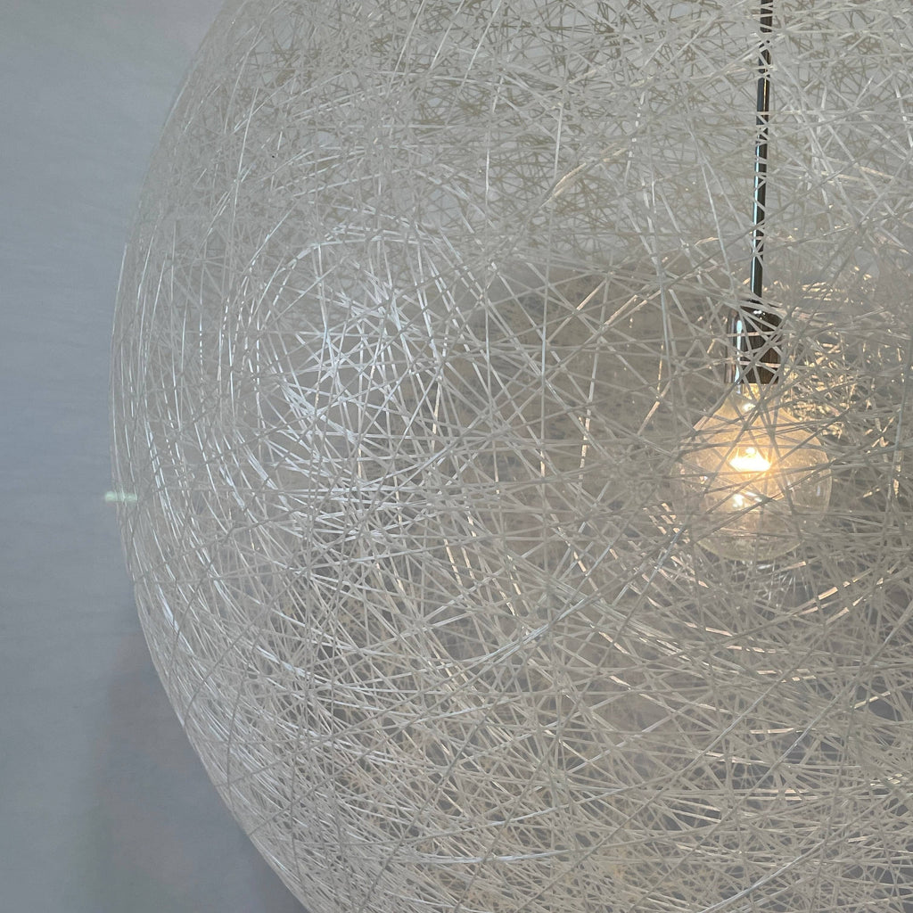 A Moooi Random Pendant suspension light with a white ball, reminiscent of the Moooi Random design, hanging from a light fixture.