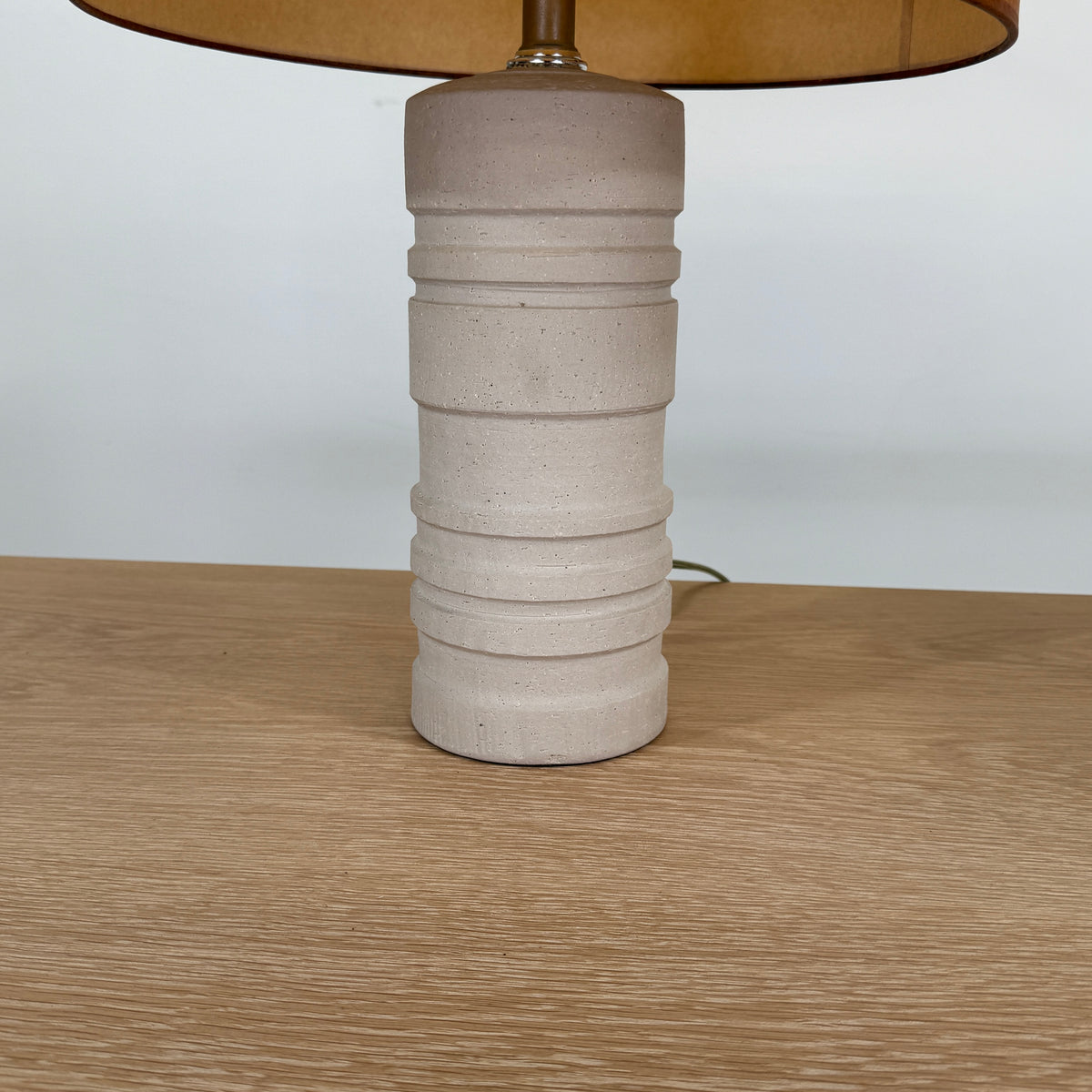 Two Shelter Brasilia Lamp by Modern Resale with textured white bases and orange cylindrical shades are displayed on a beige stone surface against a gray background.