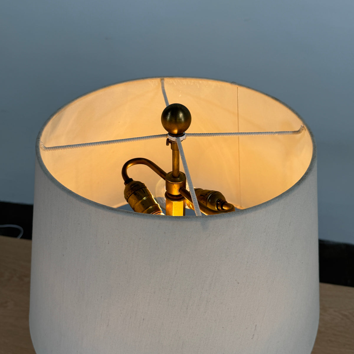 The Donghia Zig Zag Lamp Pickled Oak by Donghia features a white fabric shade and geometric wooden base, displayed on a light wood surface against a plain background.