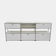 A USM Haller Storage Cabinet by USM, finished in minimal white, stands on a plain concrete floor against a light-colored wall. The modular cabinet features six closed compartments, two open shelves, and a sturdy metal frame.