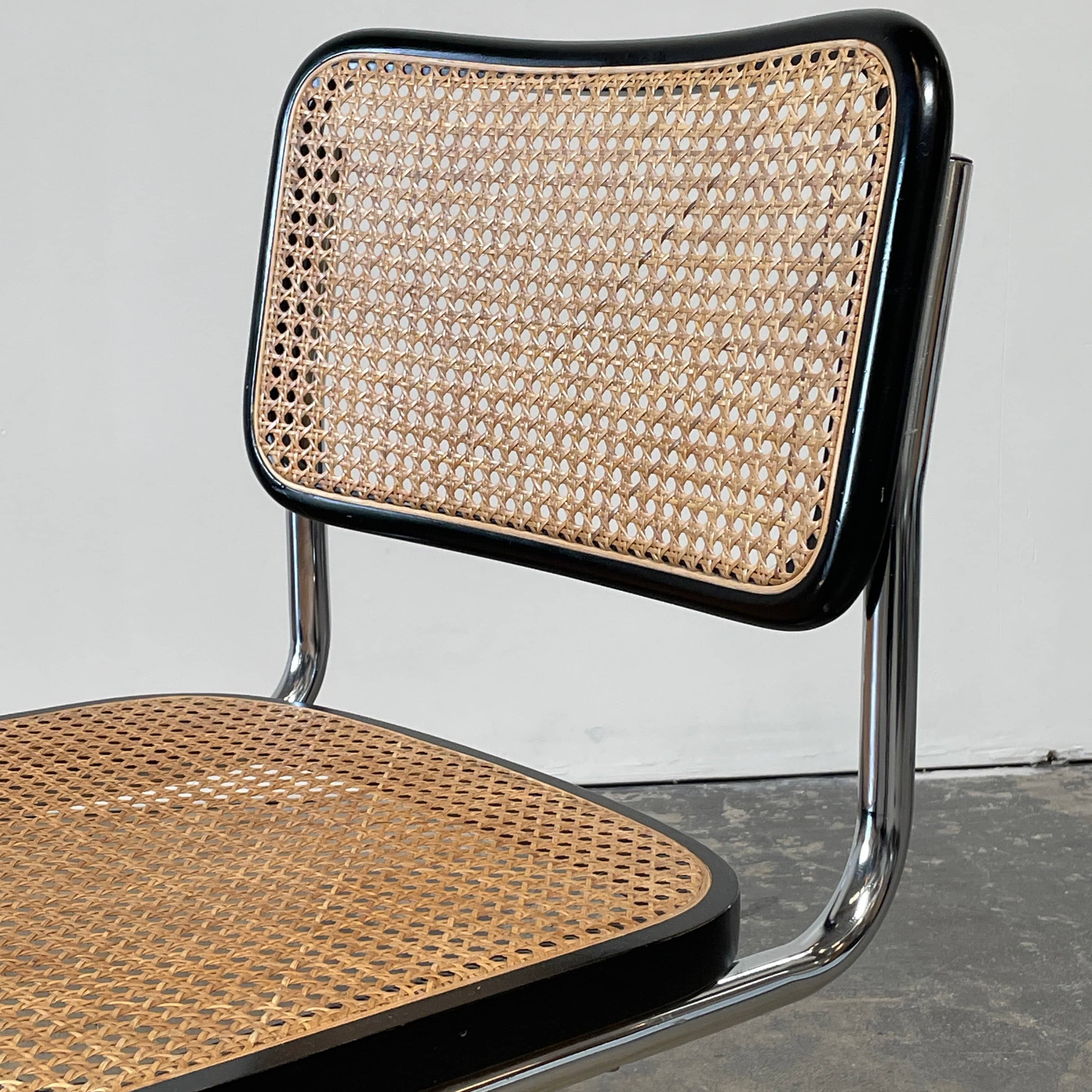 The Vintage Marcel Breuers Cesca Dining Chair showcases a chrome tubular steel frame with black edges and a woven cane seat and backrest, displayed against a plain white background.