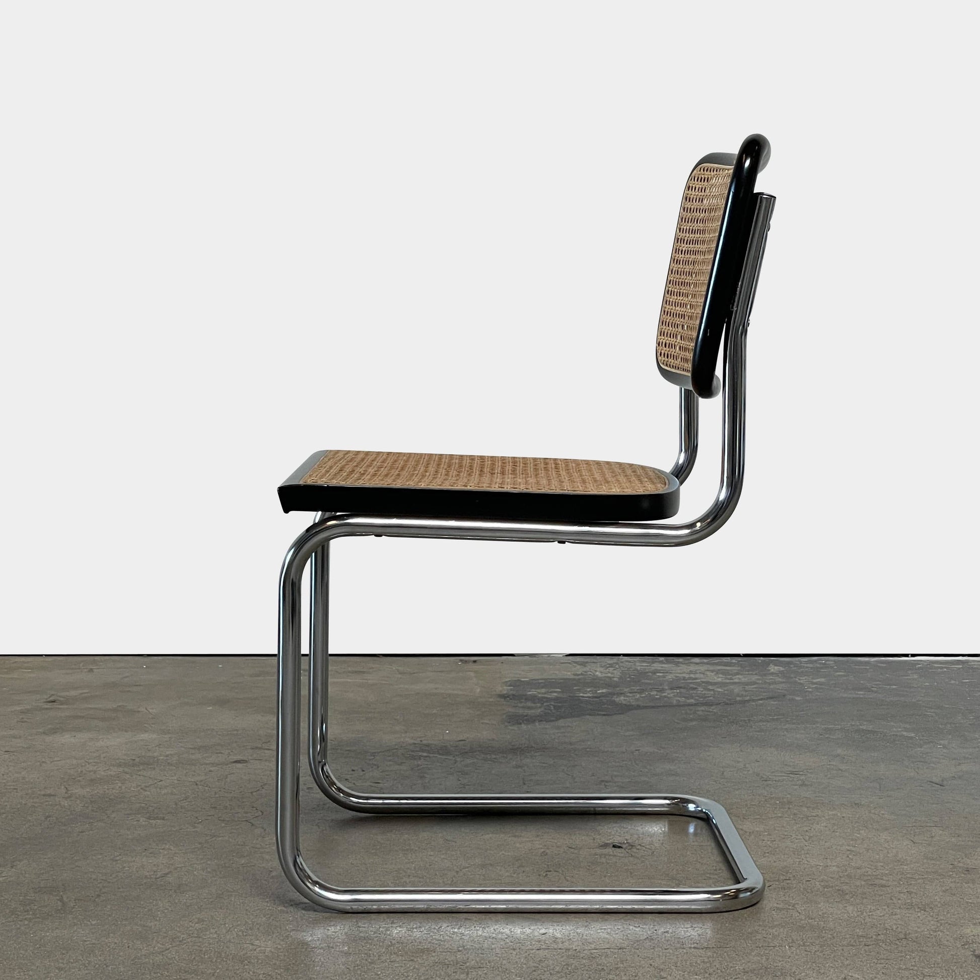 The Vintage Marcel Breuers Cesca Dining Chair showcases a chrome tubular steel frame with black edges and a woven cane seat and backrest, displayed against a plain white background.