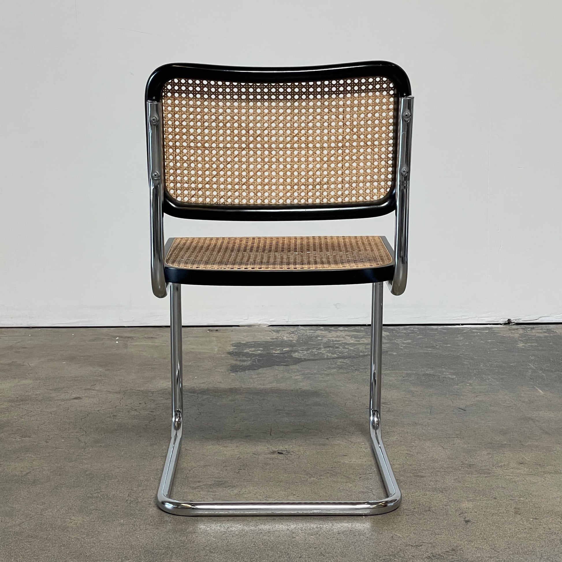 The Vintage Marcel Breuers Cesca Dining Chair showcases a chrome tubular steel frame with black edges and a woven cane seat and backrest, displayed against a plain white background.