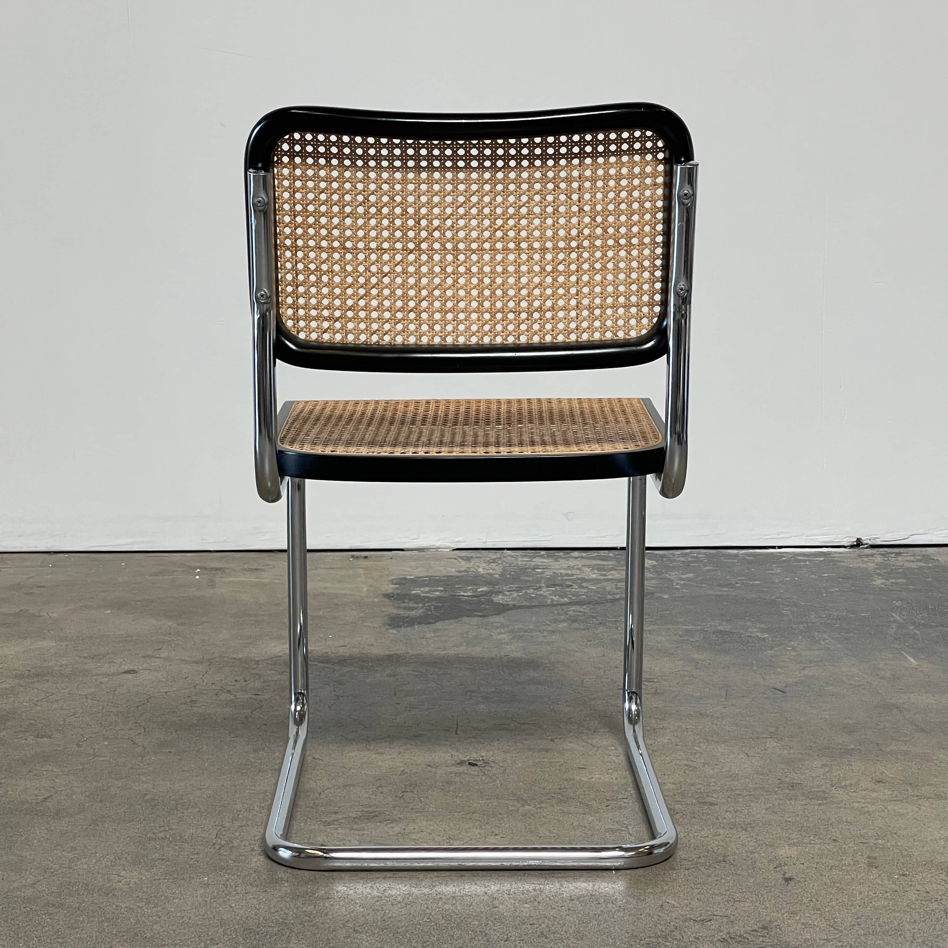 The Vintage Marcel Breuers Cesca Dining Chair showcases a chrome tubular steel frame with black edges and a woven cane seat and backrest, displayed against a plain white background.