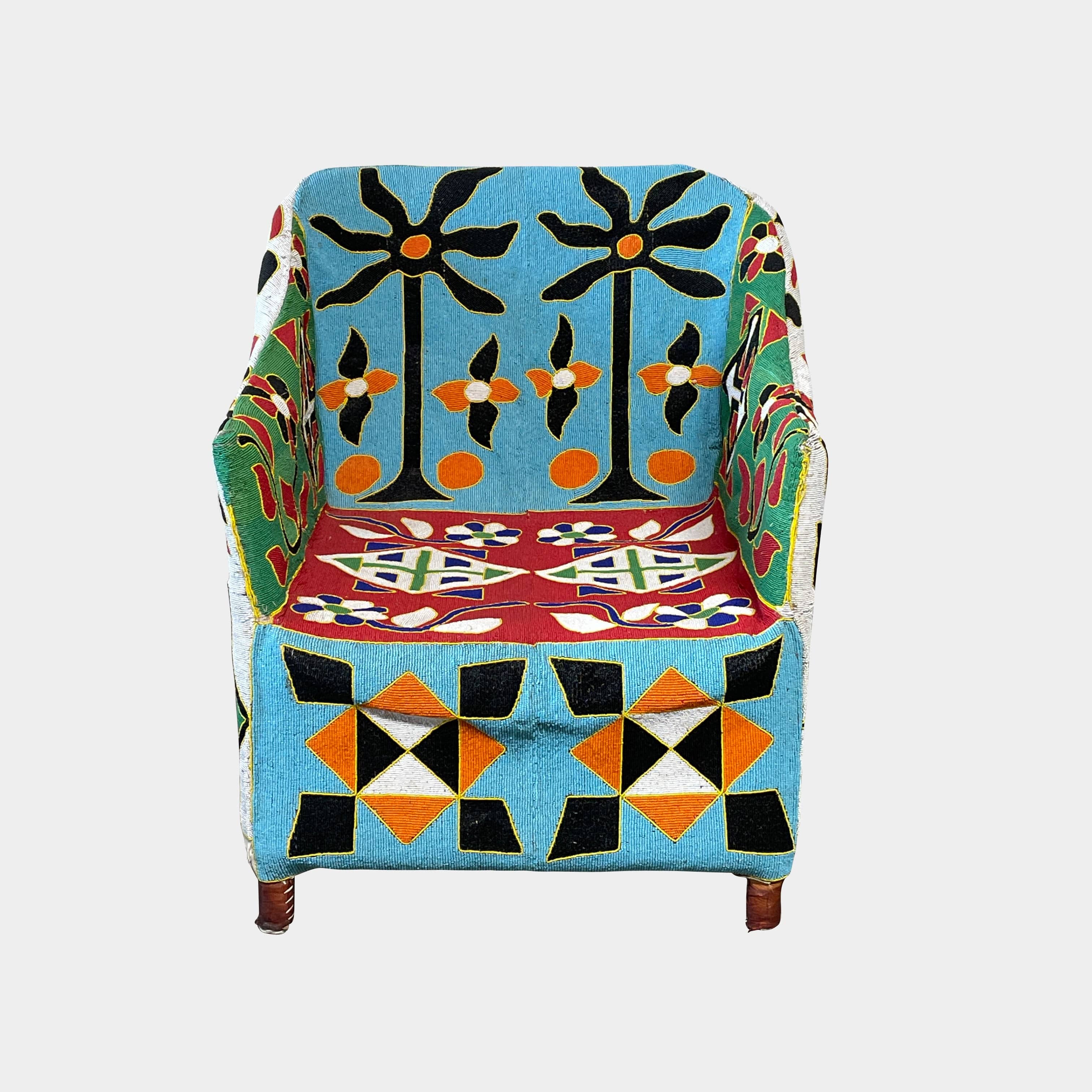 The Handmade Hand Beaded African Yoruba Chair (on hold) features a high backrest, wooden legs, and vibrant upholstery with multicolored geometric and floral patterns inspired by West African artistry.