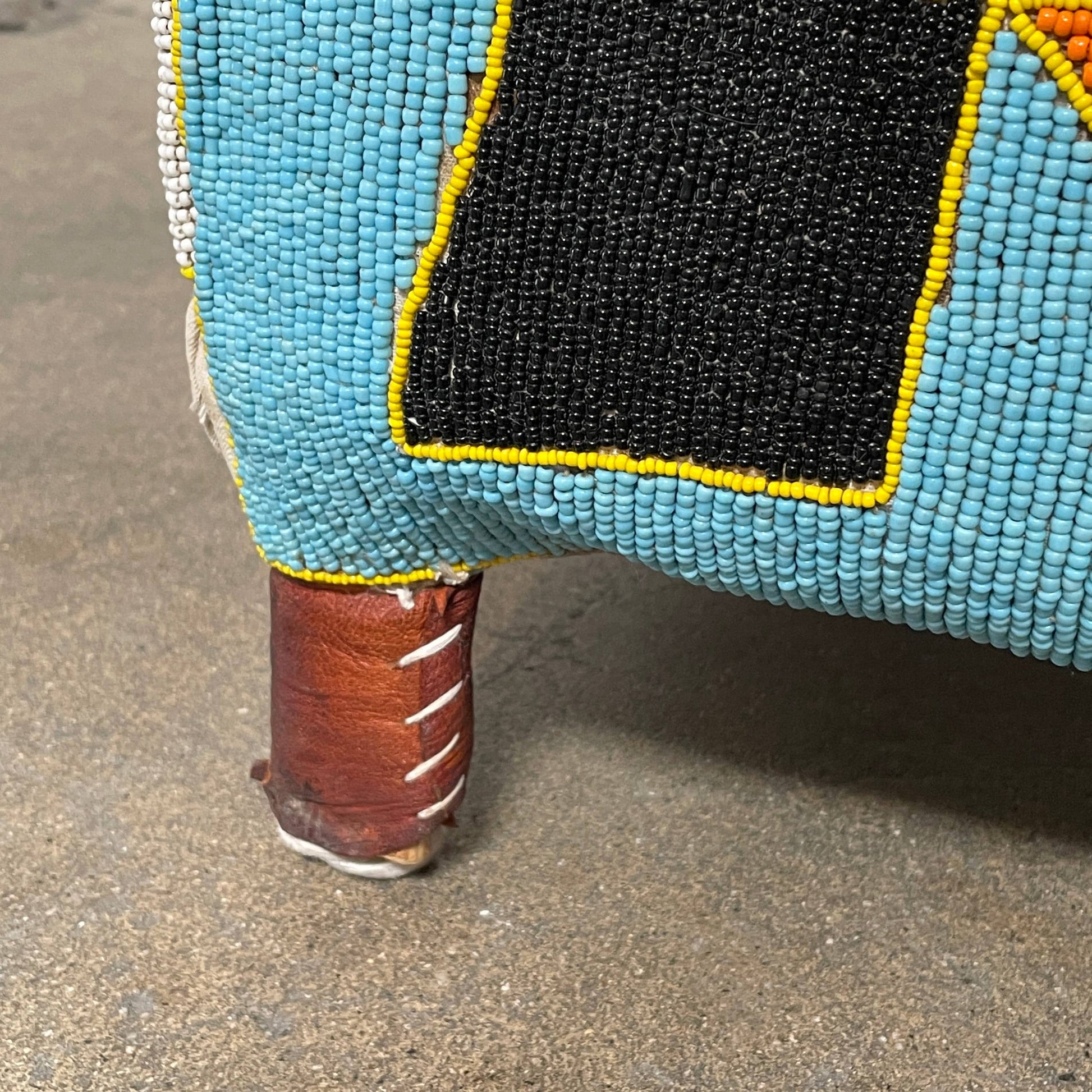 The Handmade Hand Beaded African Yoruba Chair (on hold) features a high backrest, wooden legs, and vibrant upholstery with multicolored geometric and floral patterns inspired by West African artistry.